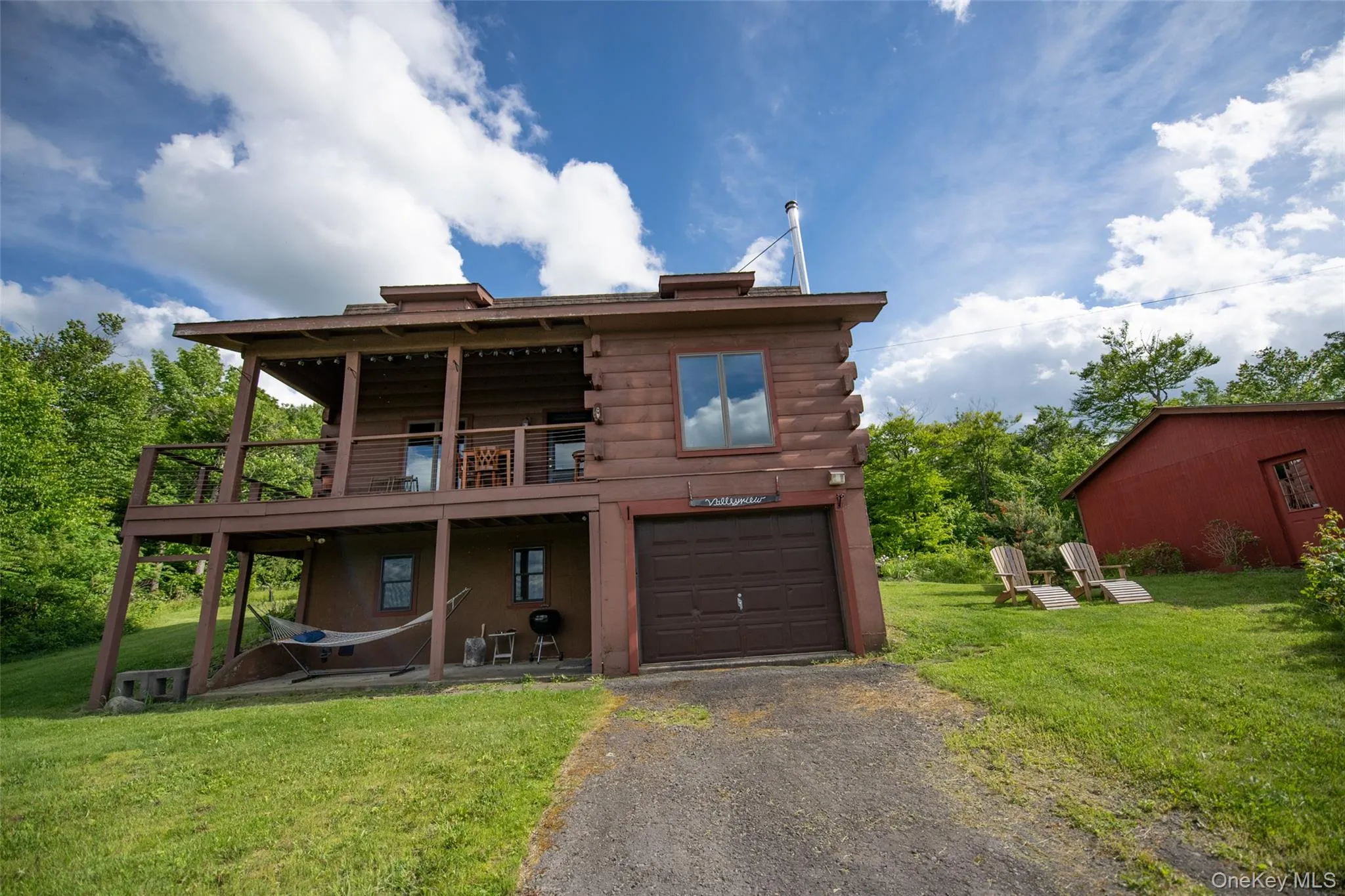 Log cabin with a front lawn, asphalt driveway, a garage, and log exterior Log cabin with a front lawn, asphalt driveway, a garage, and log exterior