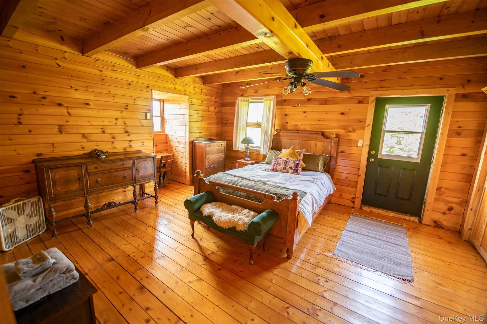 Bedroom with hardwood / wood-style floors, multiple windows, a wooden ceiling with exposed beams, wood walls, and a ceiling fan Bedroom with hardwood / wood-style floors, multiple windows, a wooden ceiling with exposed beams, wood walls, and a ceiling fan