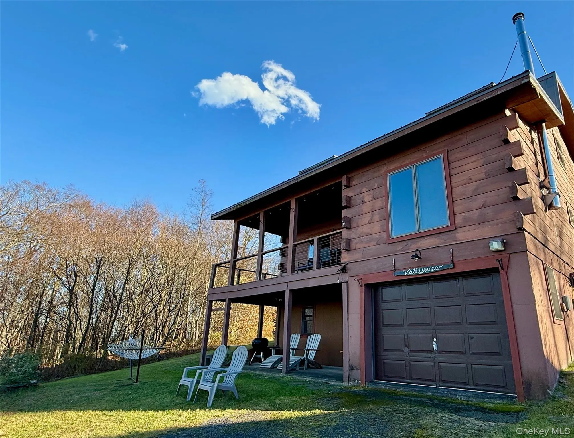 Back of property with a lawn, a balcony, log siding, and a garage Back of property with a lawn, a balcony, log siding, and a garage