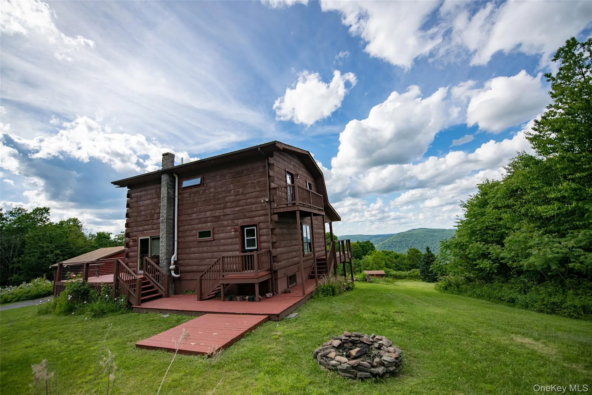 Back of house featuring a fire pit, a yard, a chimney, and a deck Back of house featuring a fire pit, a yard, a chimney, and a deck