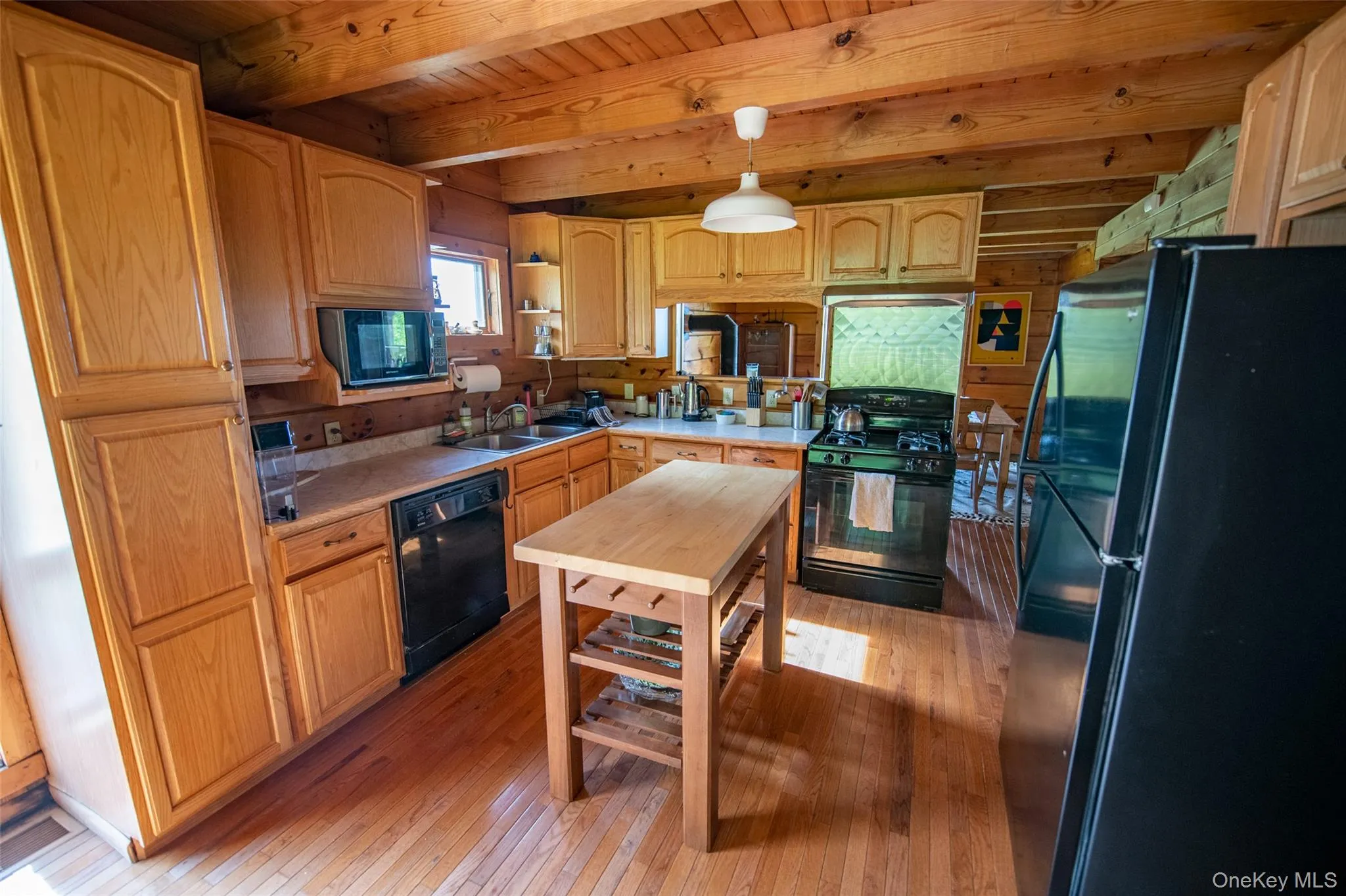 Kitchen with black appliances, light wood-style floors, light countertops, a wood ceiling with exposed beams, and pendant lighting Kitchen with black appliances, light wood-style floors, light countertops, a wood ceiling with exposed beams, and pendant lighting