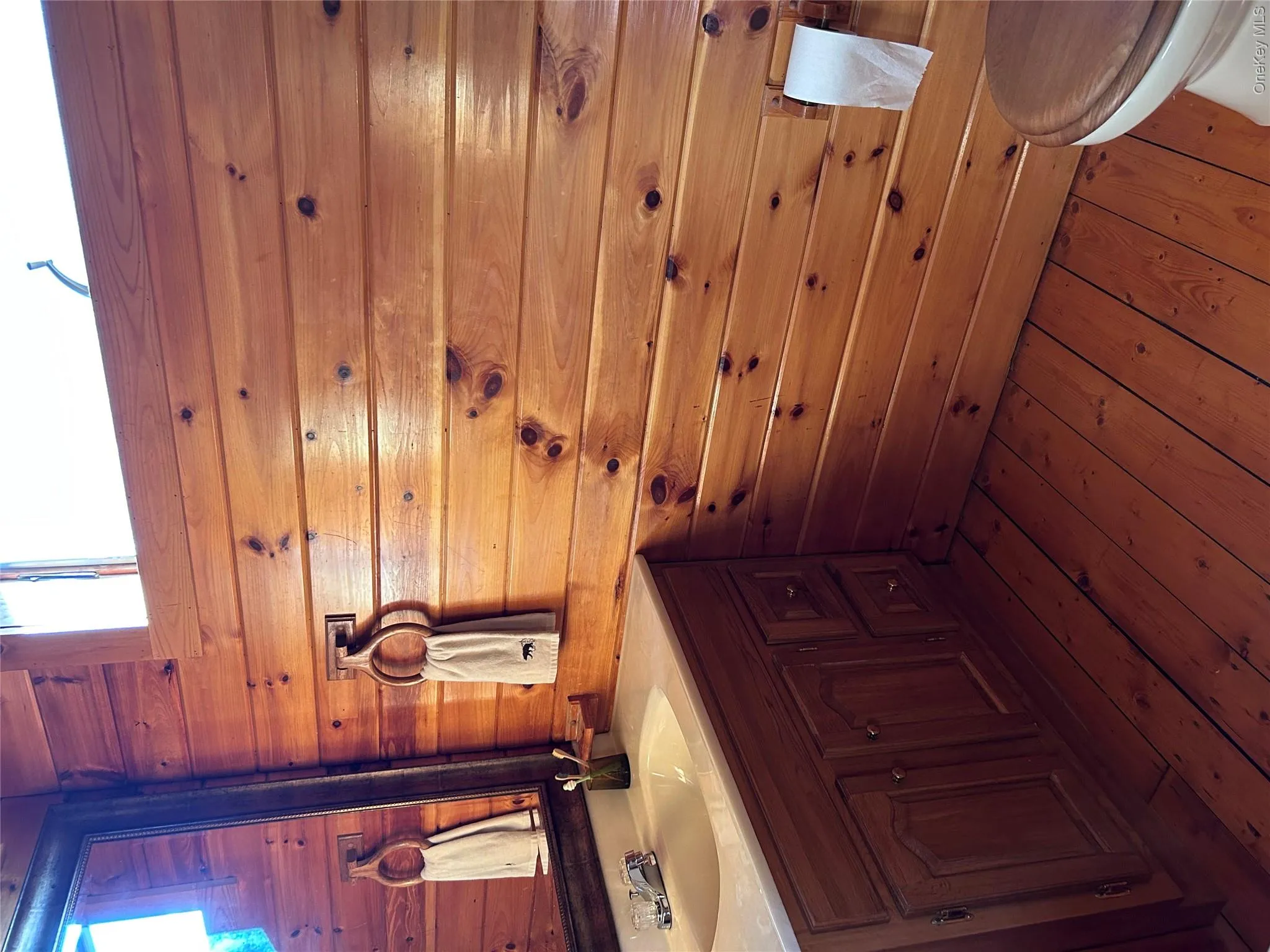 Half bathroom featuring wooden walls, vanity, and dark wood-style flooring Half bathroom featuring wooden walls, vanity, and dark wood-style flooring