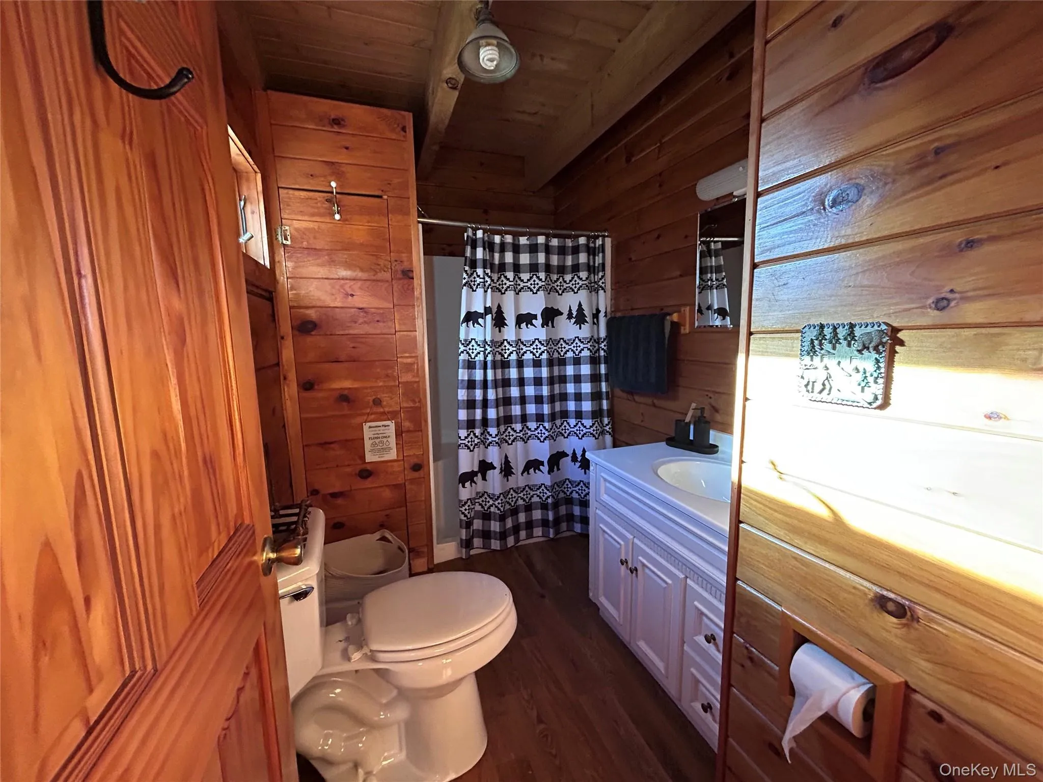 Bathroom featuring vanity, wood walls, dark wood finished floors, and wooden ceiling Bathroom featuring vanity, wood walls, dark wood finished floors, and wooden ceiling