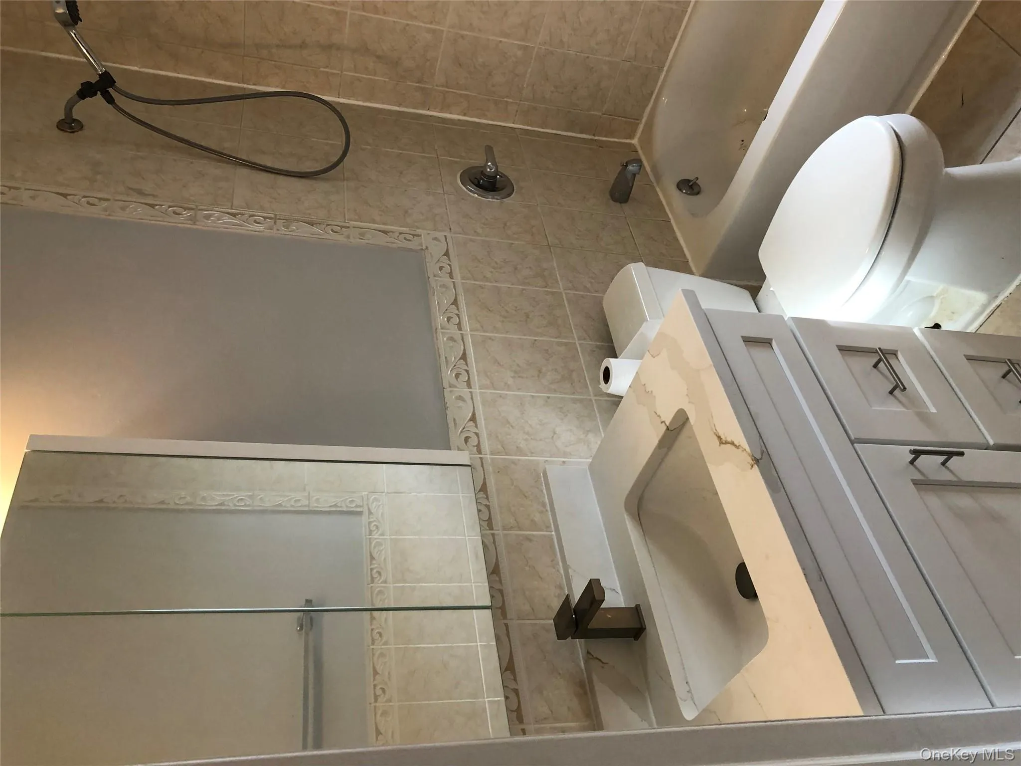 Full bathroom featuring vanity, shower / tub combination, tile walls, and light tile patterned floors Full bathroom featuring vanity, shower / tub combination, tile walls, and light tile patterned floors