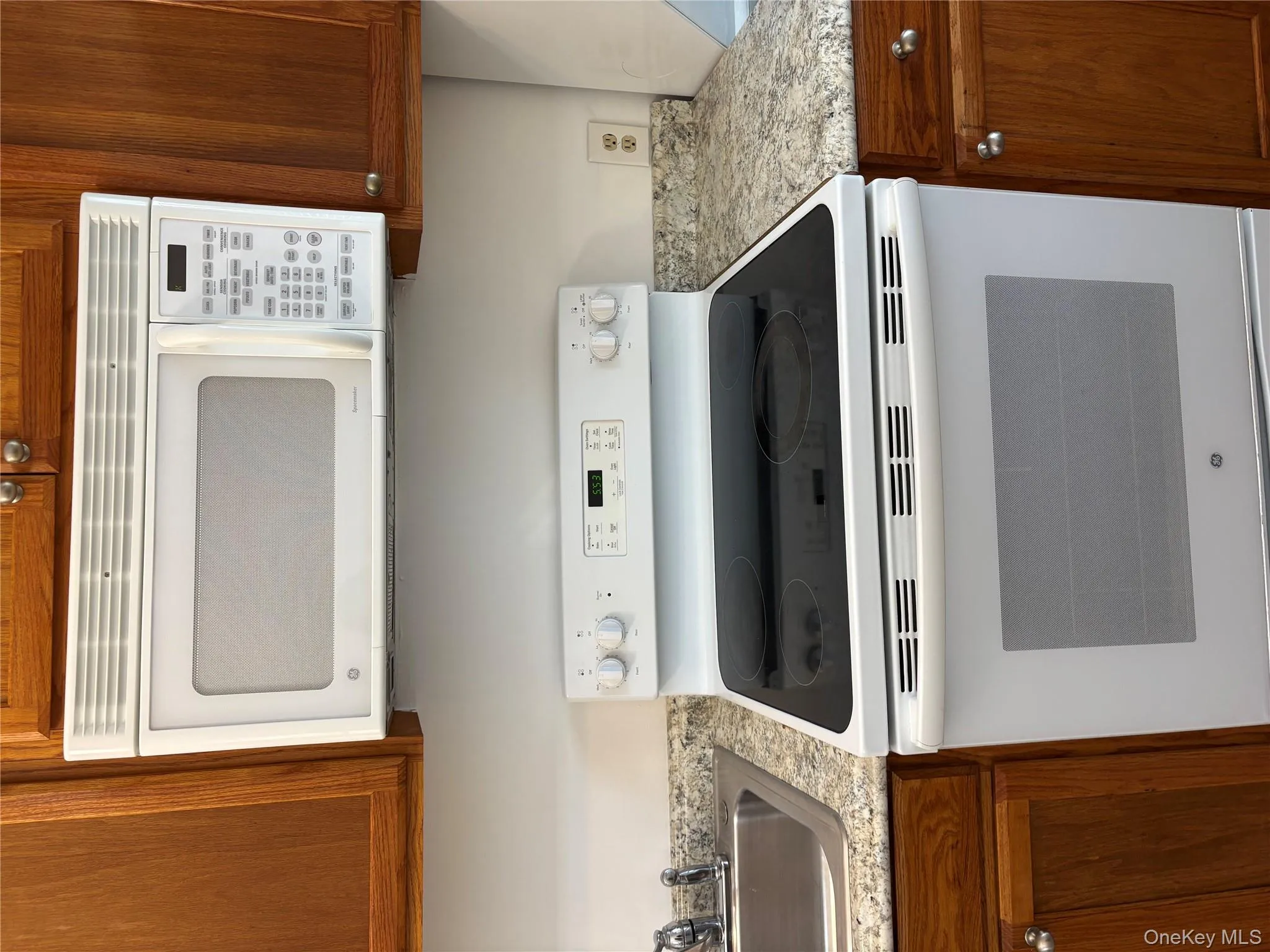 Kitchen featuring white range with electric cooktop and brown cabinets Kitchen featuring white range with electric cooktop and brown cabinets