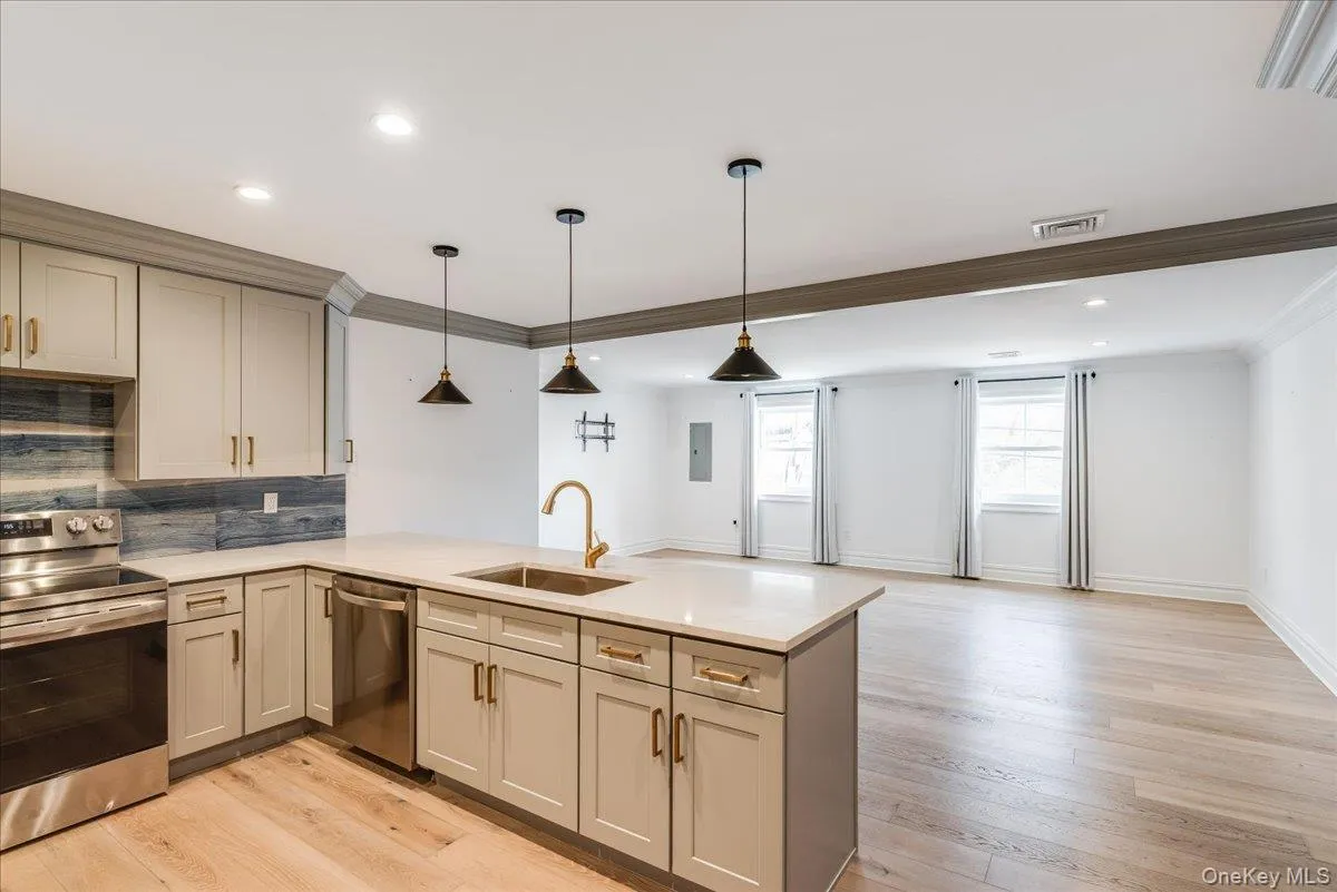 Kitchen with appliances with stainless steel finishes, tasteful backsplash, hanging light fixtures, light wood finished floors, and recessed lighting Kitchen with appliances with stainless steel finishes, tasteful backsplash, hanging light fixtures, light wood finished floors, and recessed lighting