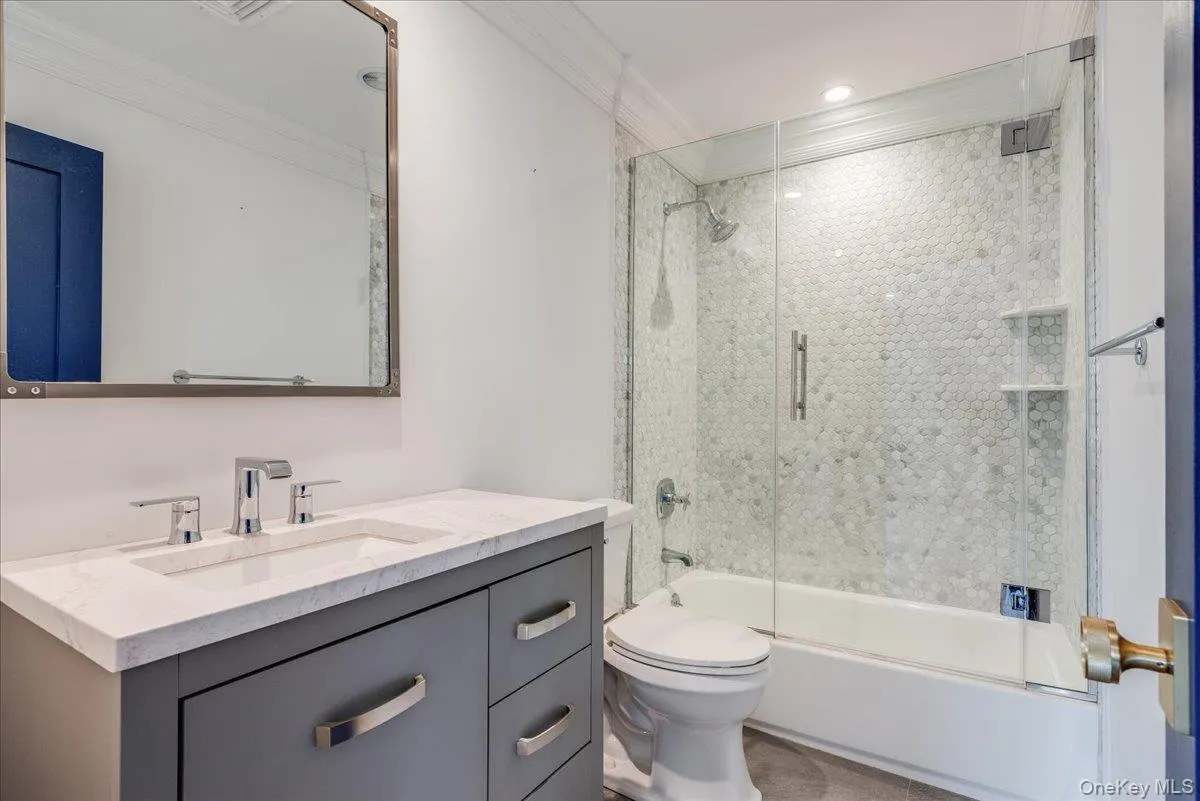 Full bathroom with vanity, crown molding, and bath / shower combo with glass door Full bathroom with vanity, crown molding, and bath / shower combo with glass door