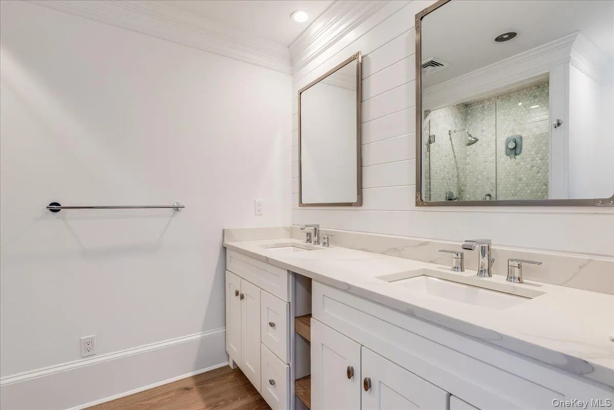 Full bathroom featuring a shower stall, crown molding, double vanity, and light wood-type flooring Full bathroom featuring a shower stall, crown molding, double vanity, and light wood-type flooring