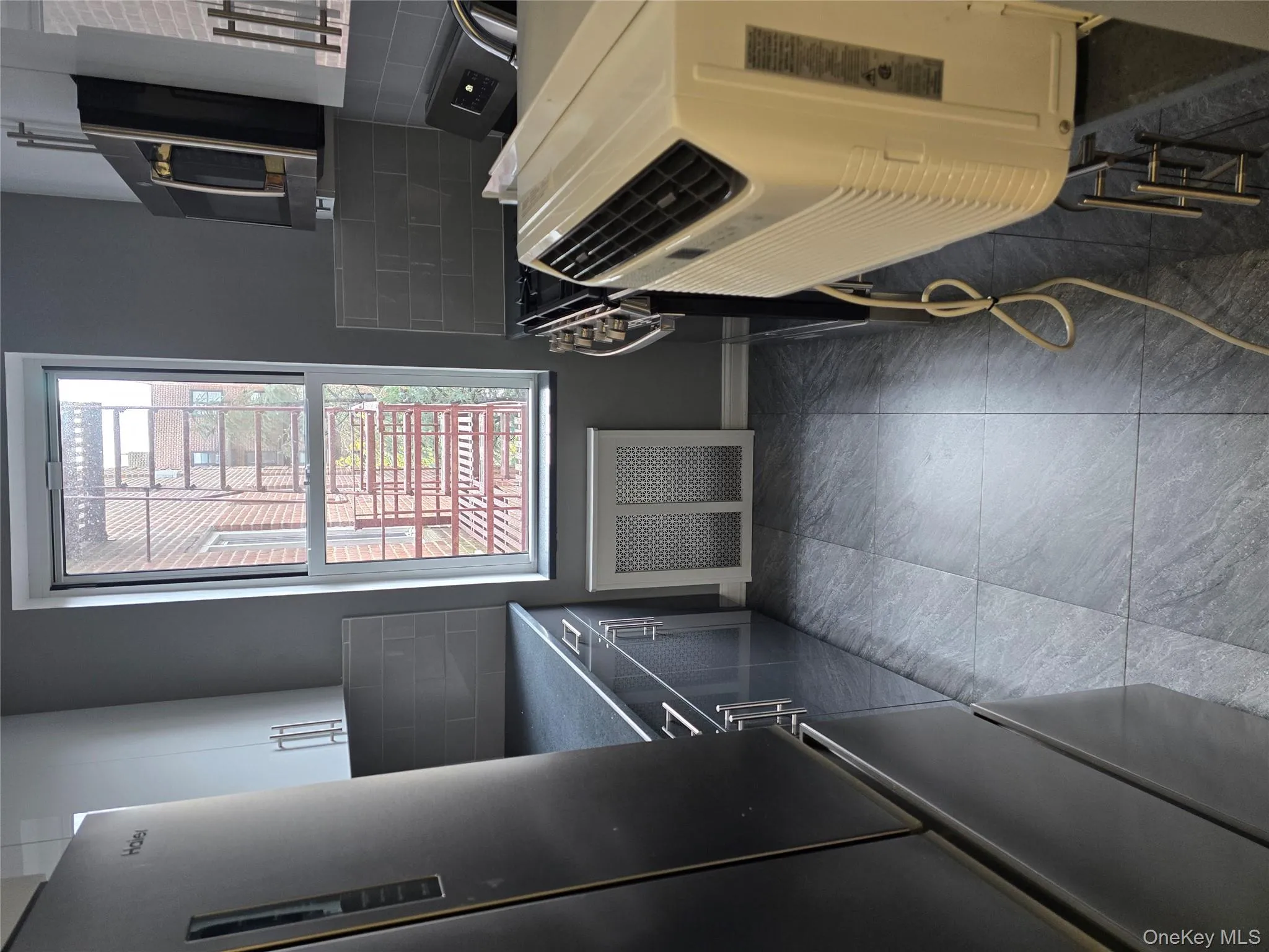 Kitchen featuring tasteful backsplash, stainless steel refrigerator, pet washing area, stove, and dark countertops Kitchen featuring tasteful backsplash, stainless steel refrigerator, pet washing area, stove, and dark countertops