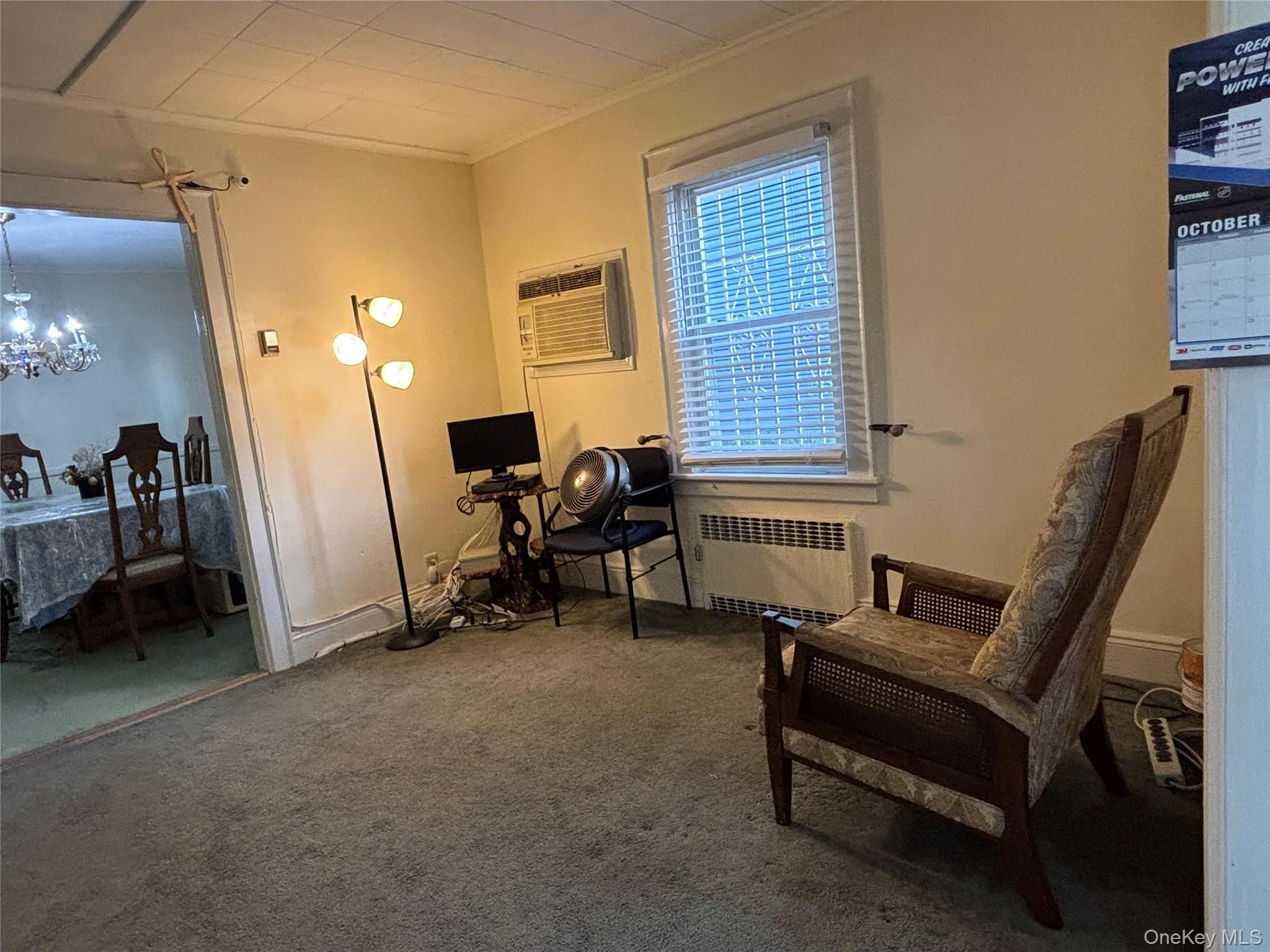 Sitting room with carpet, ornamental molding, radiator, a chandelier, and a wall mounted air conditioner Sitting room with carpet, ornamental molding, radiator, a chandelier, and a wall mounted air conditioner