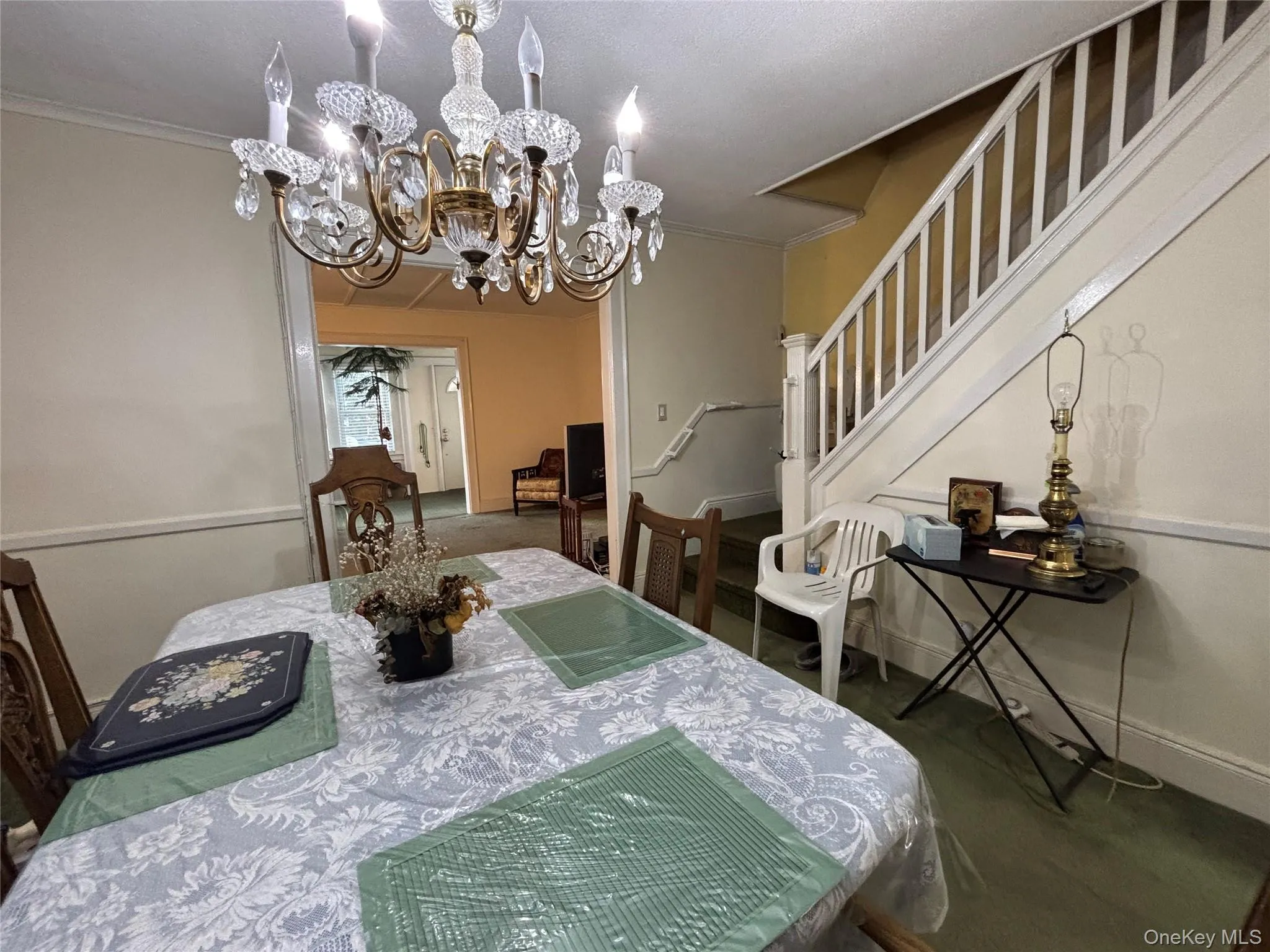 Dining room featuring stairway, a chandelier, and crown molding Dining room featuring stairway, a chandelier, and crown molding
