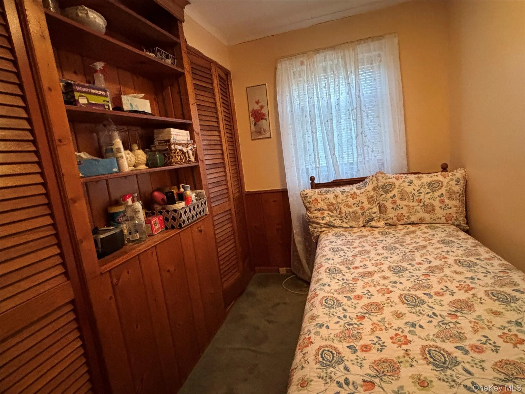 Bedroom featuring dark colored carpet, wood walls, a wainscoted wall, and a closet Bedroom featuring dark colored carpet, wood walls, a wainscoted wall, and a closet