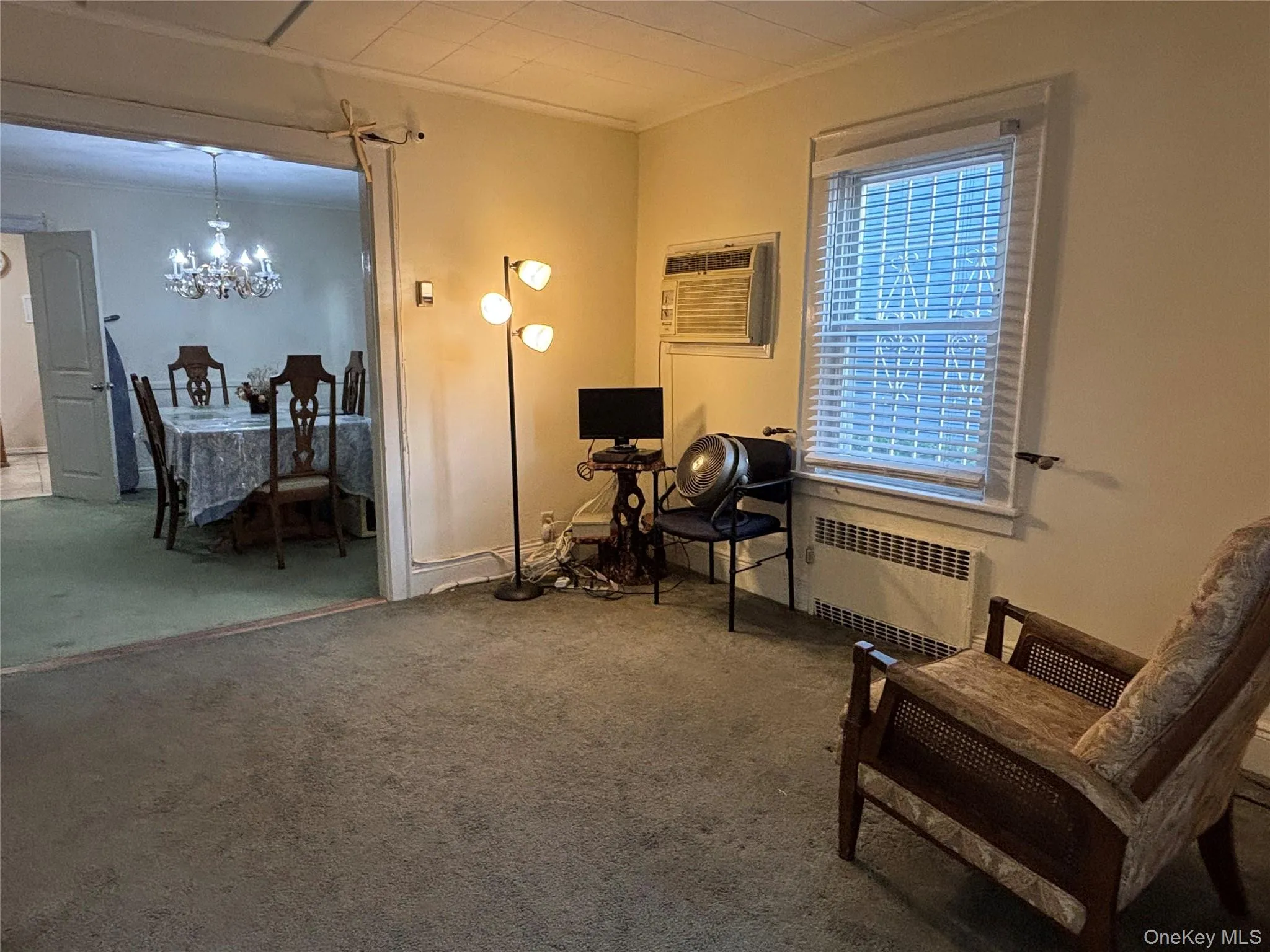 Sitting room featuring radiator, carpet, a chandelier, crown molding, and a wall unit AC Sitting room featuring radiator, carpet, a chandelier, crown molding, and a wall unit AC