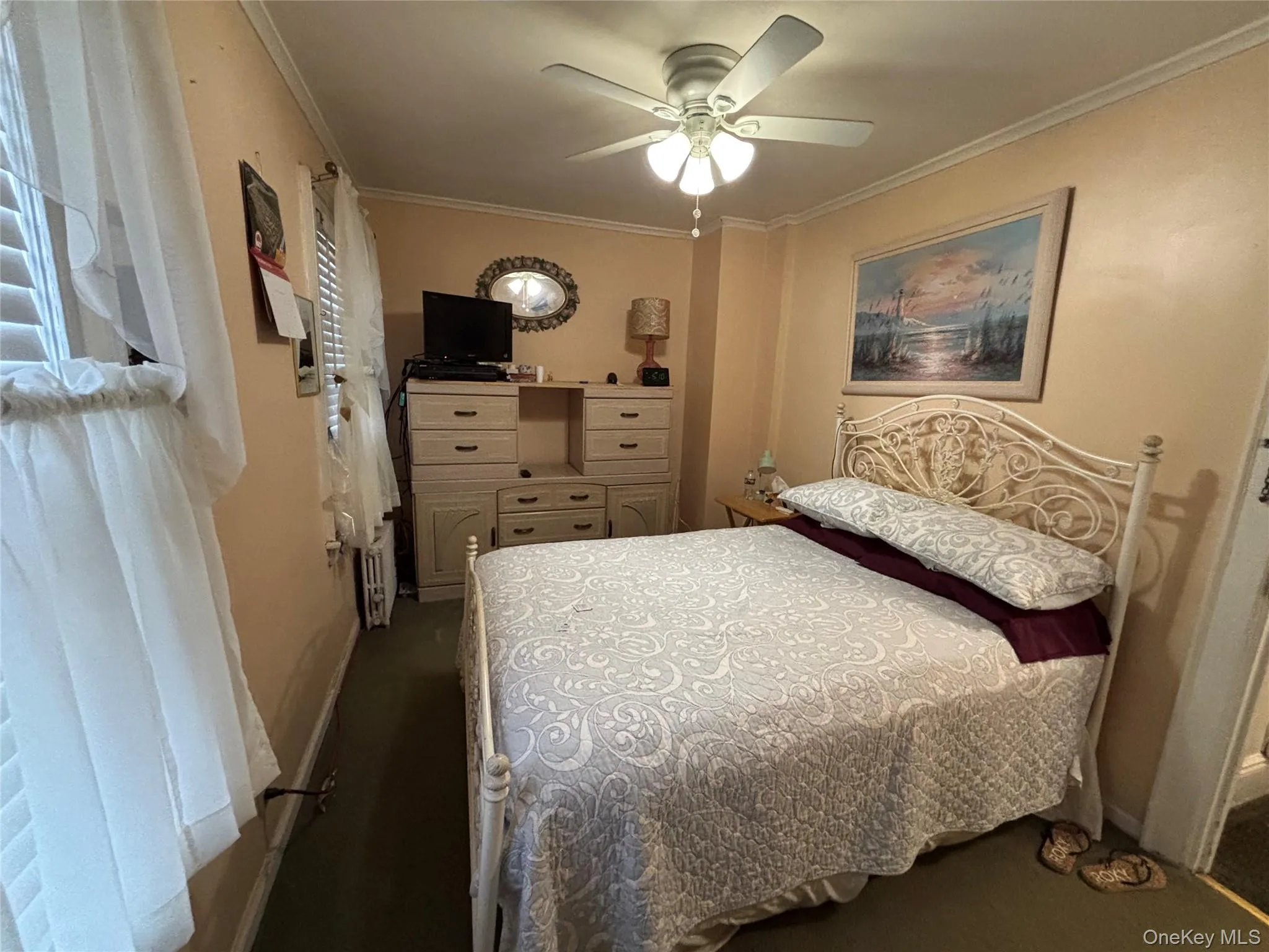 Bedroom featuring crown molding, a ceiling fan, and radiator heating unit Bedroom featuring crown molding, a ceiling fan, and radiator heating unit