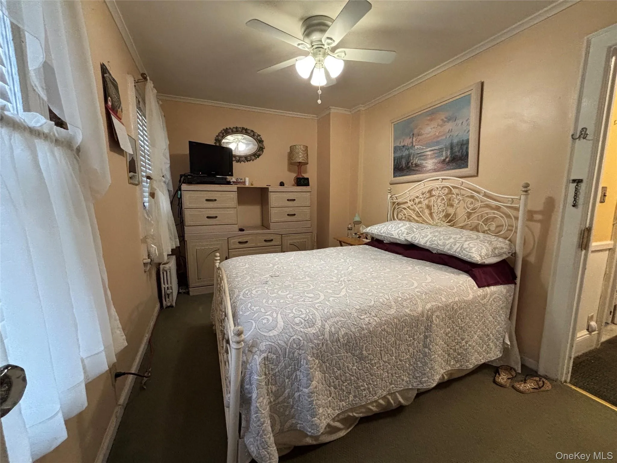 Bedroom featuring ornamental molding, dark carpet, and ceiling fan Bedroom featuring ornamental molding, dark carpet, and ceiling fan