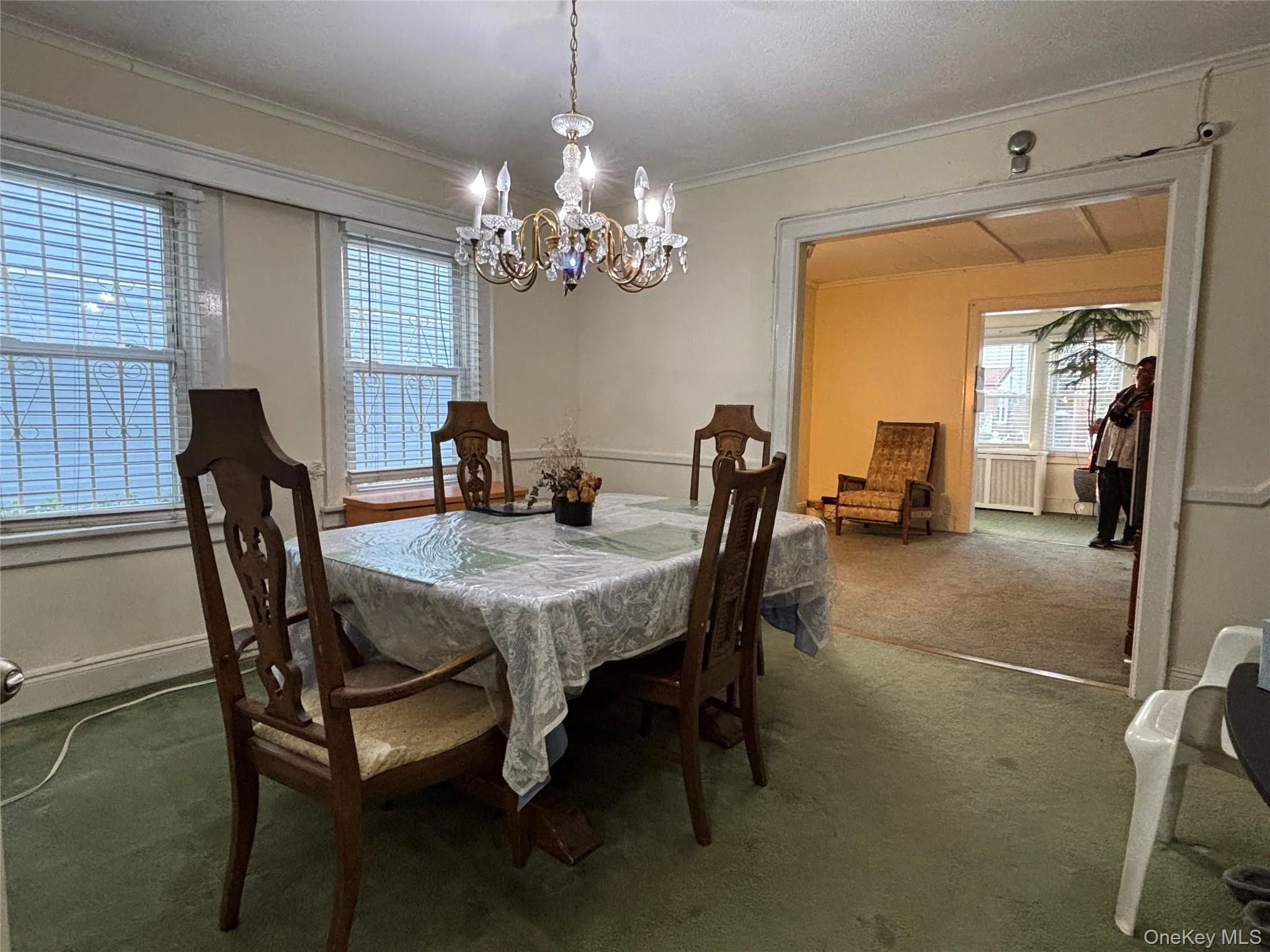 Dining room featuring dark colored carpet, a chandelier, crown molding, and radiator Dining room featuring dark colored carpet, a chandelier, crown molding, and radiator