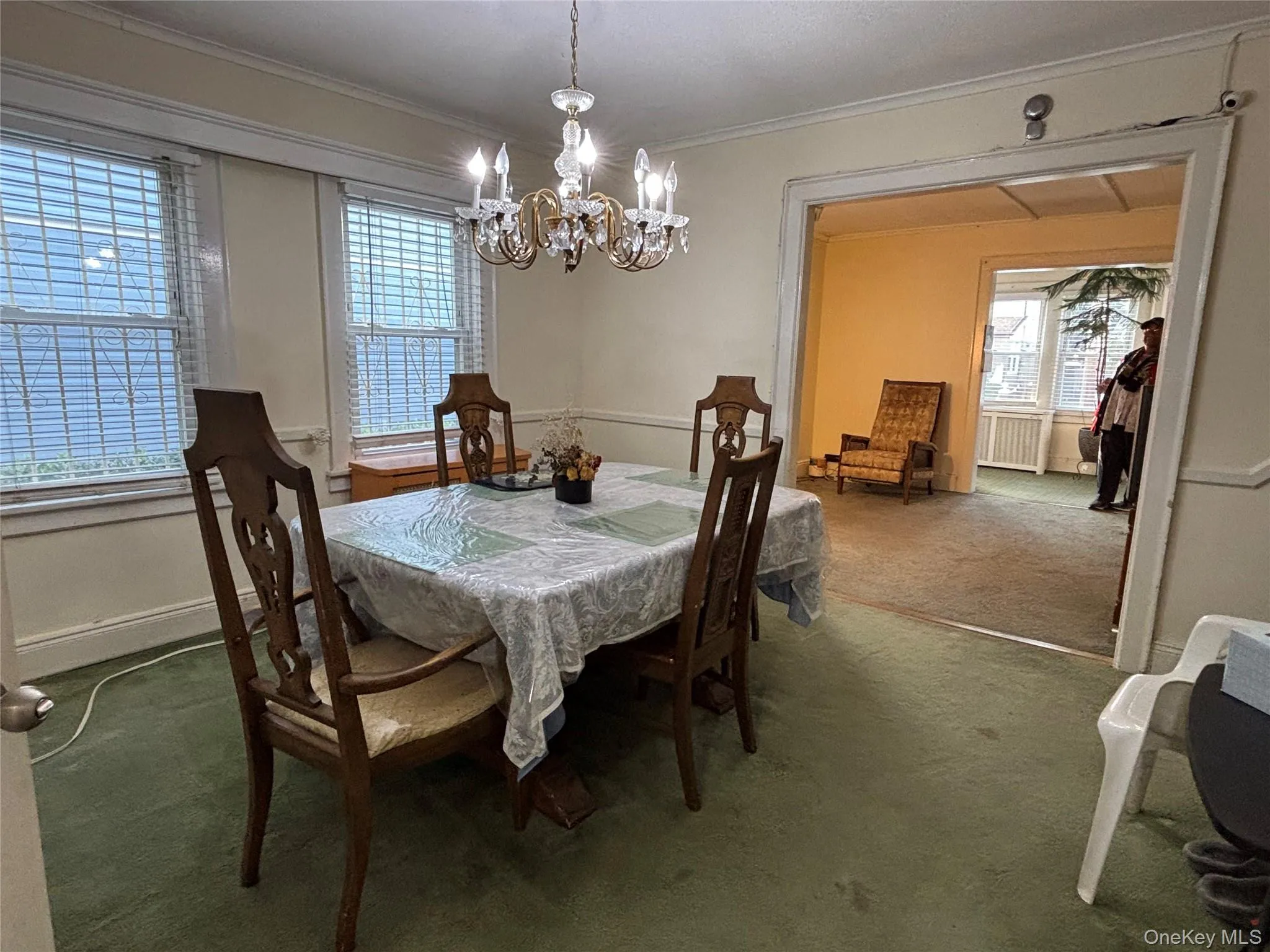 Dining space featuring dark carpet, ornamental molding, a chandelier, and radiator Dining space featuring dark carpet, ornamental molding, a chandelier, and radiator