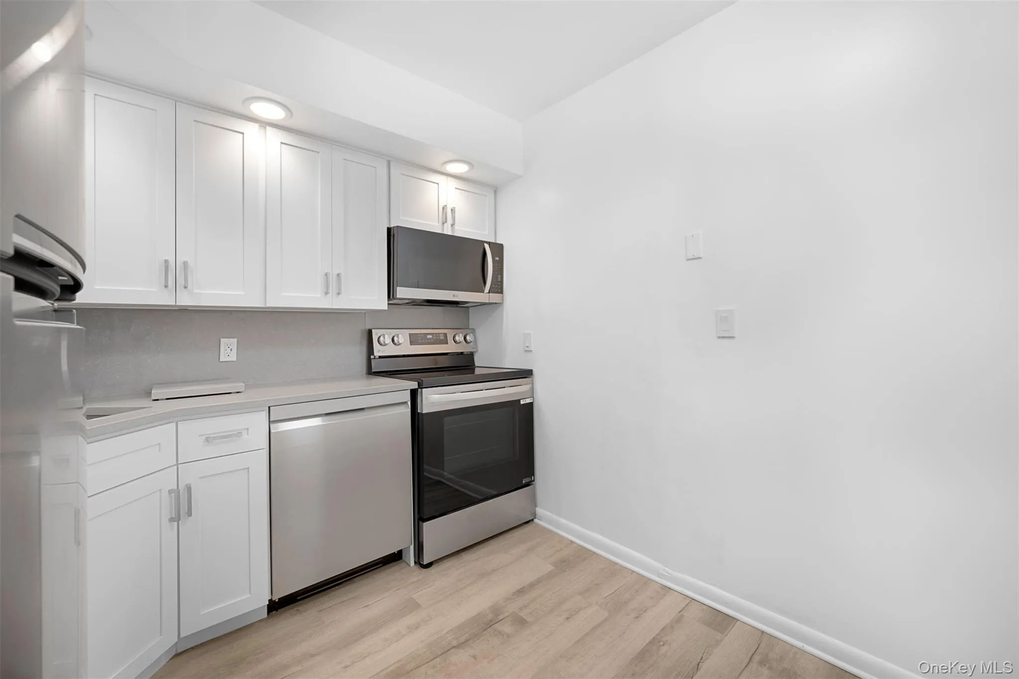 Eat-In-Kitchen featuring appliances with stainless steel finishes, white cabinets, and light wood-style flooring Eat-In-Kitchen featuring appliances with stainless steel finishes, white cabinets, and light wood-style flooring