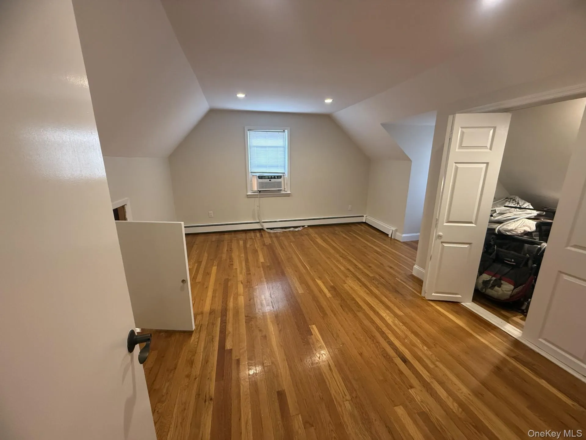 Bonus room with vaulted ceiling, light wood-style flooring, a baseboard radiator, and cooling unit Bonus room with vaulted ceiling, light wood-style flooring, a baseboard radiator, and cooling unit