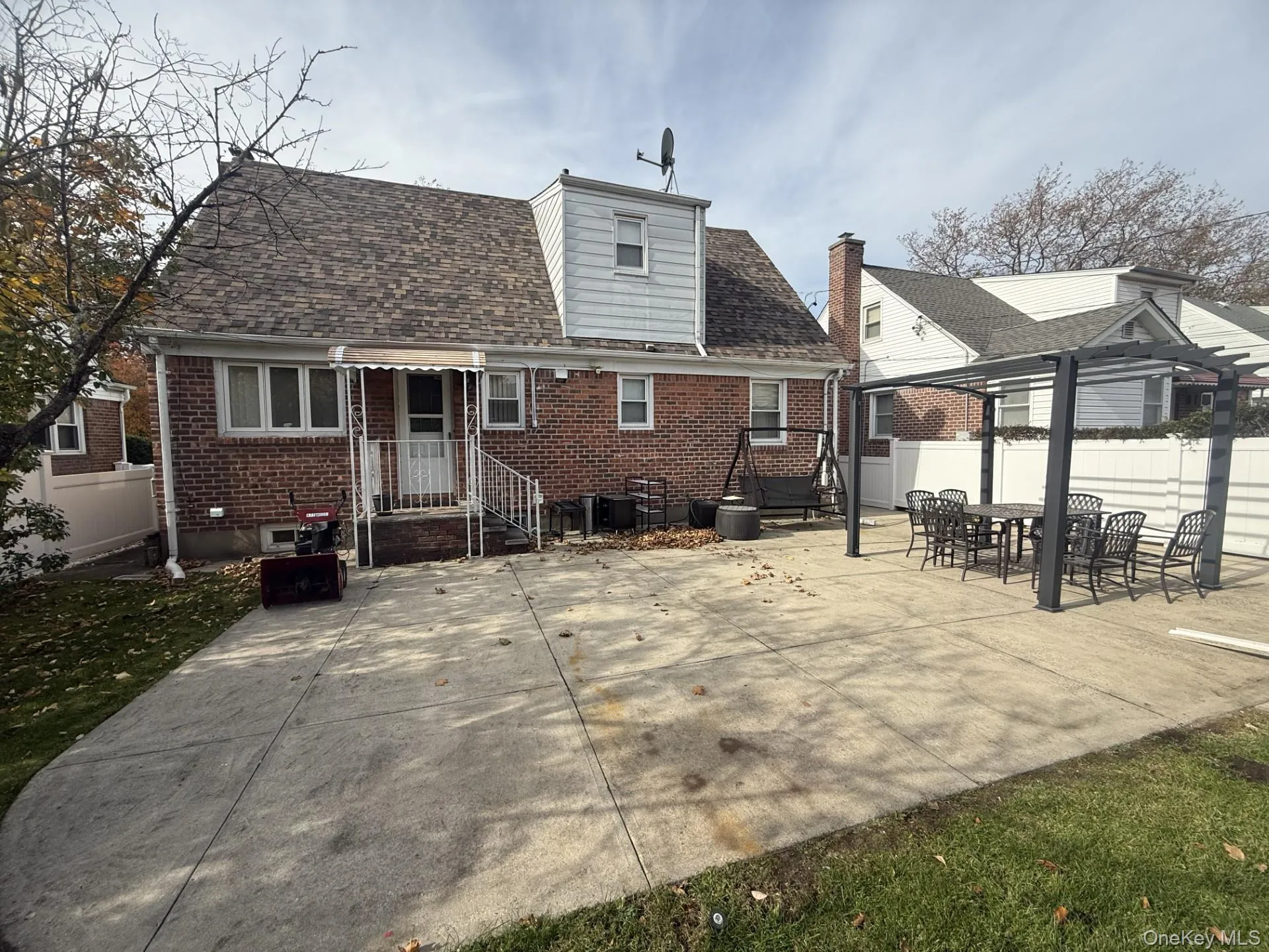 Rear view of property featuring a patio, brick siding, and roof with shingles Rear view of property featuring a patio, brick siding, and roof with shingles