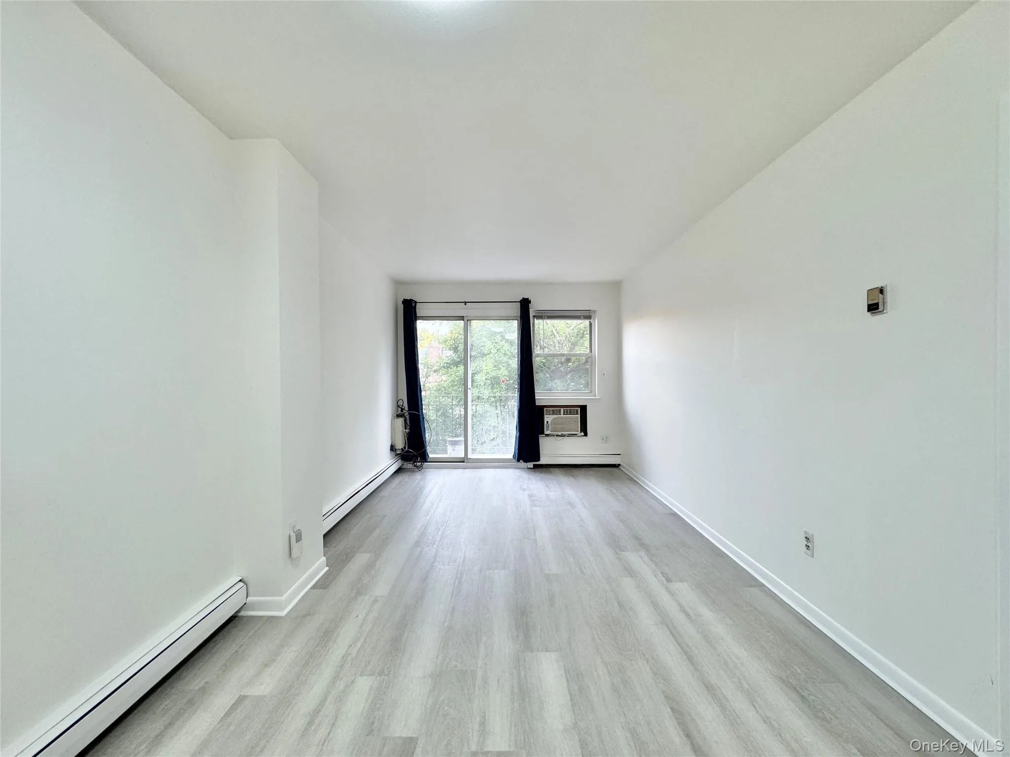 Spare room featuring a baseboard radiator and light wood finished floors Spare room featuring a baseboard radiator and light wood finished floors