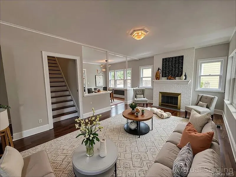 Living area with wood finished floors, a brick fireplace, and stairs Living area with wood finished floors, a brick fireplace, and stairs