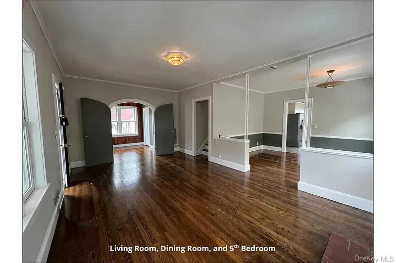 Spare room with arched walkways, dark wood-type flooring, and crown molding Spare room with arched walkways, dark wood-type flooring, and crown molding
