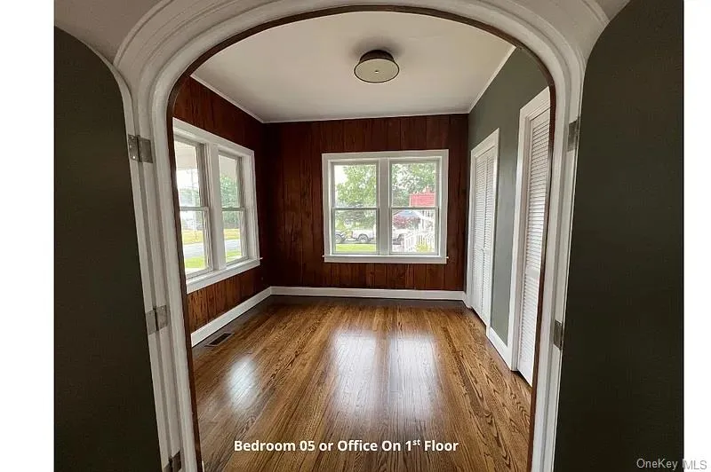 Spare room featuring arched walkways, dark wood finished floors, and wooden walls Spare room featuring arched walkways, dark wood finished floors, and wooden walls