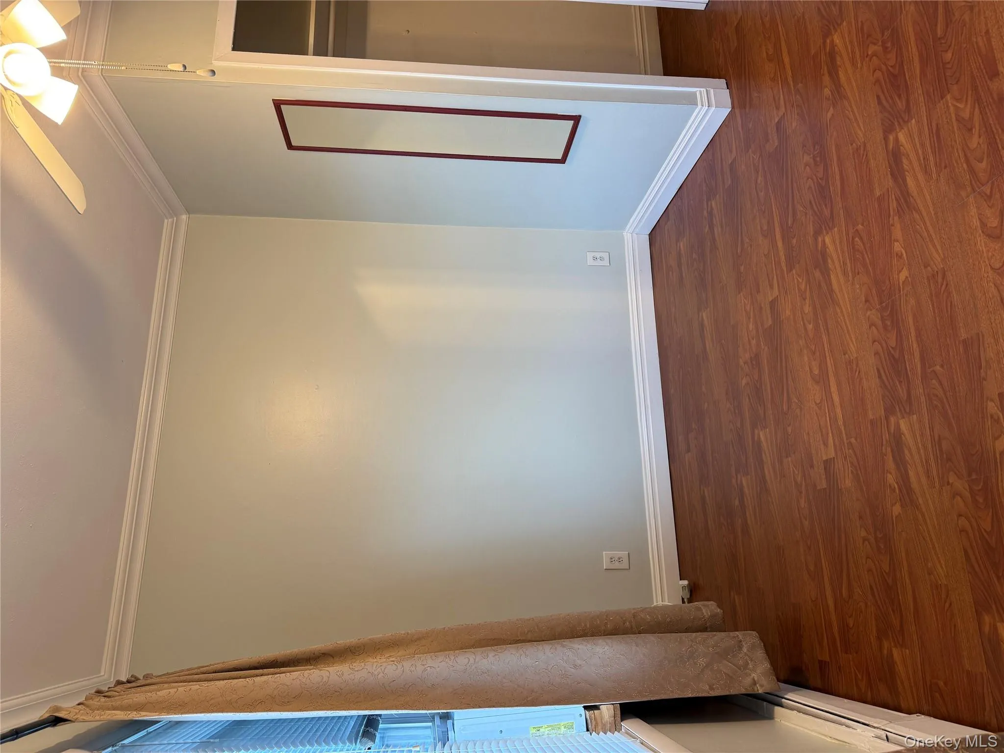 Unfurnished bedroom with ornamental molding, dark wood-style flooring, ceiling fan, baseboard heating, and a closet Unfurnished bedroom with ornamental molding, dark wood-style flooring, ceiling fan, baseboard heating, and a closet