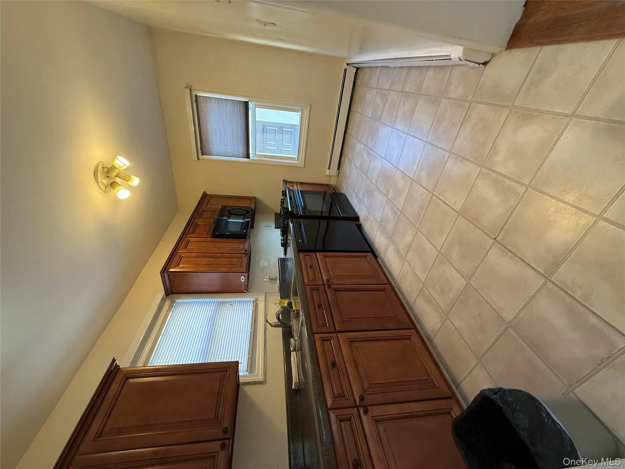 Kitchen with dark countertops, black stove, light tile patterned flooring, and healthy amount of natural light Kitchen with dark countertops, black stove, light tile patterned flooring, and healthy amount of natural light