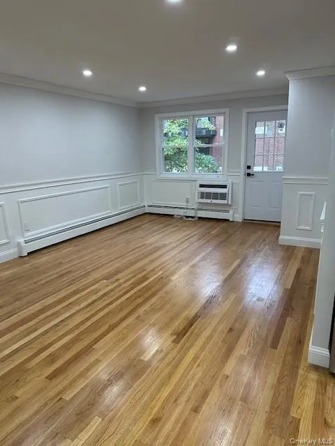 Spare room with a decorative wall, light wood-style floors, recessed lighting, crown molding, and a baseboard heating unit Spare room with a decorative wall, light wood-style floors, recessed lighting, crown molding, and a baseboard heating unit