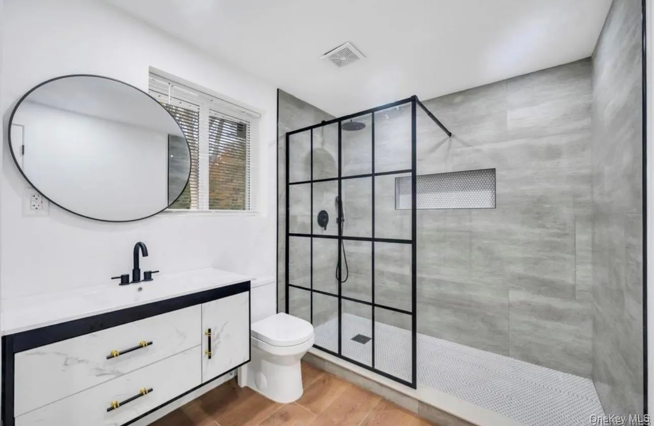 Bathroom featuring vanity, a walk in shower, and light wood-style flooring Bathroom featuring vanity, a walk in shower, and light wood-style flooring