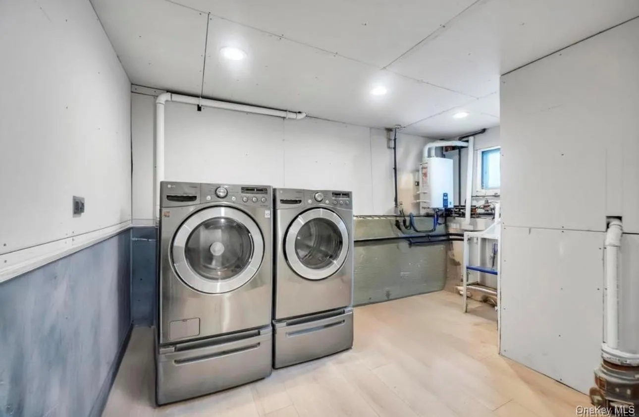 Laundry area featuring light wood-type flooring, water heater, washing machine and clothes dryer, and recessed lighting Laundry area featuring light wood-type flooring, water heater, washing machine and clothes dryer, and recessed lighting