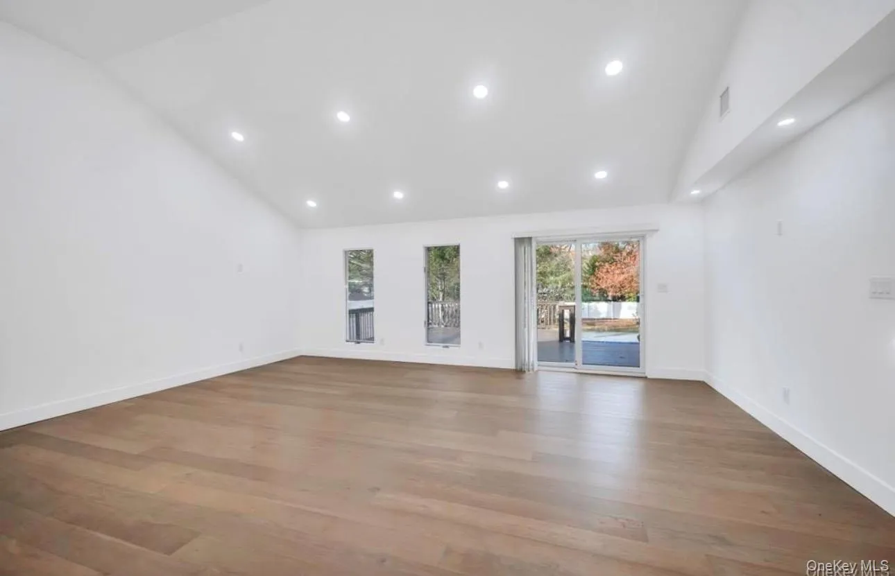 Empty room with light wood-style floors, high vaulted ceiling, and recessed lighting Empty room with light wood-style floors, high vaulted ceiling, and recessed lighting