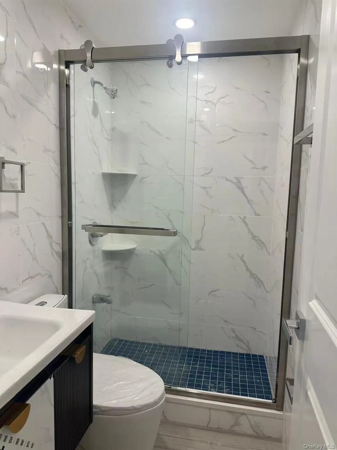 Bathroom with vanity, a marble finish shower, and tile walls Bathroom with vanity, a marble finish shower, and tile walls