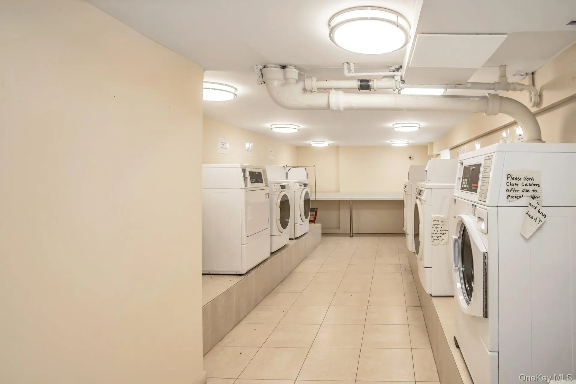 Shared laundry area with light tile patterned flooring and independent washer and dryer Shared laundry area with light tile patterned flooring and independent washer and dryer