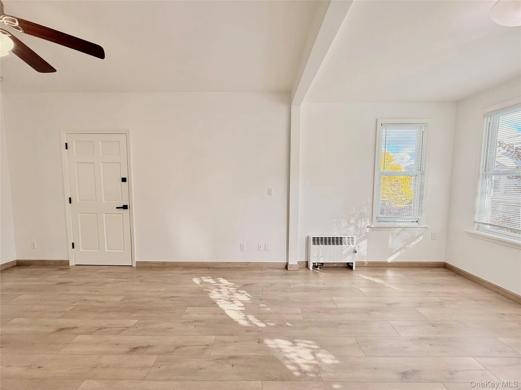 Unfurnished room with light wood-style flooring, radiator, and a ceiling fan Unfurnished room with light wood-style flooring, radiator, and a ceiling fan