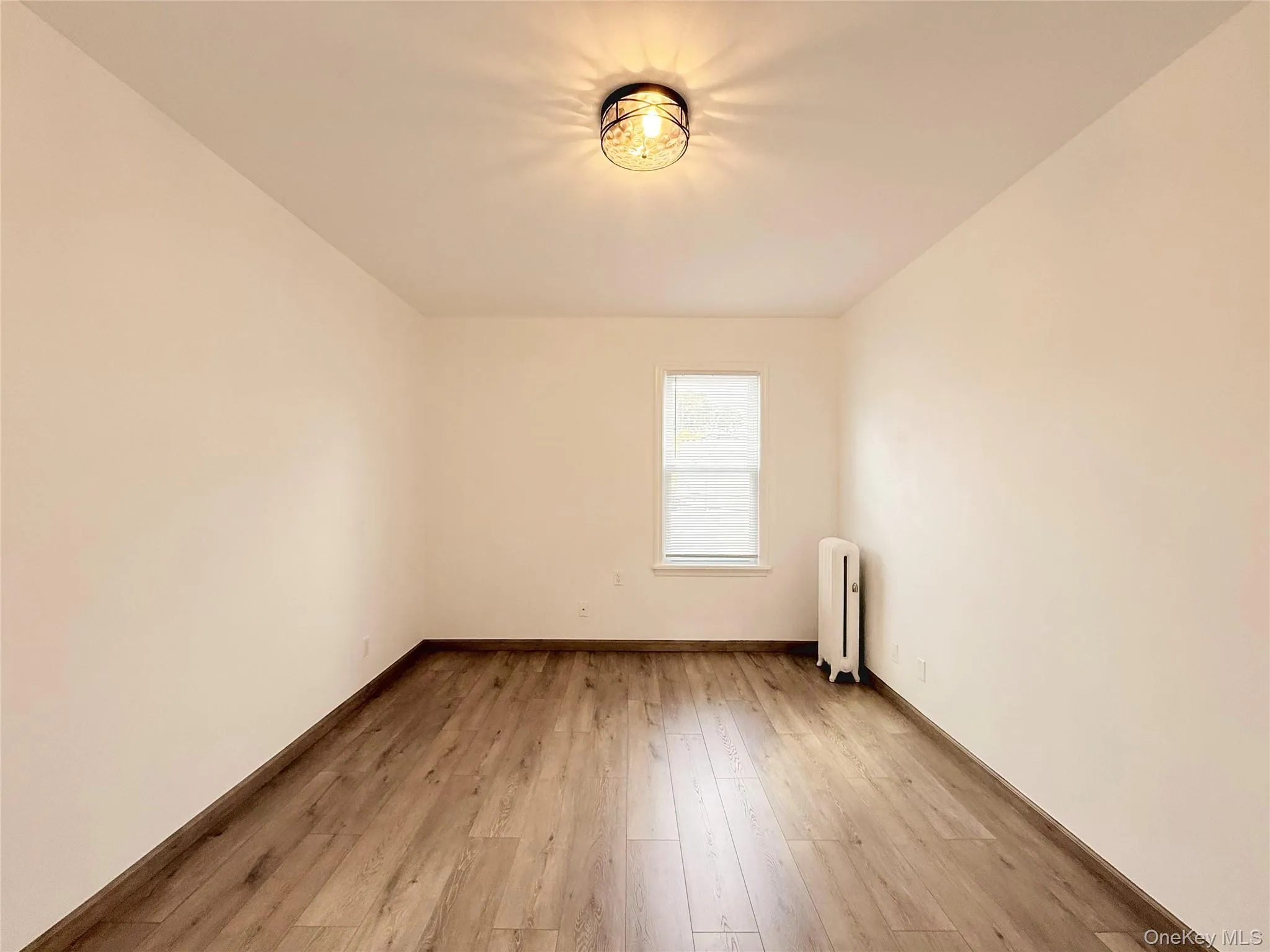 Empty room featuring radiator heating unit and light wood-style floors Empty room featuring radiator heating unit and light wood-style floors