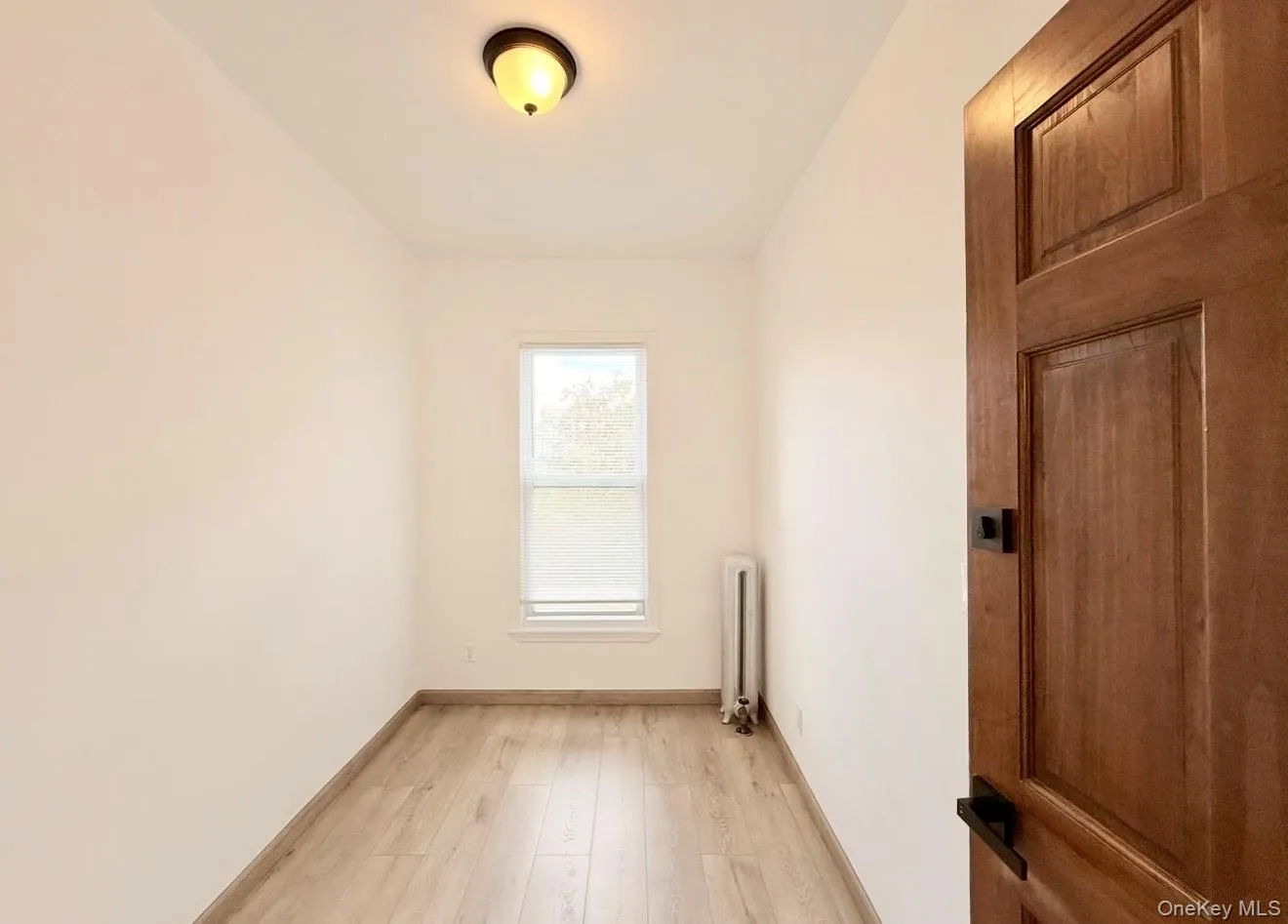 Spare room featuring light wood-style flooring and radiator heating unit Spare room featuring light wood-style flooring and radiator heating unit