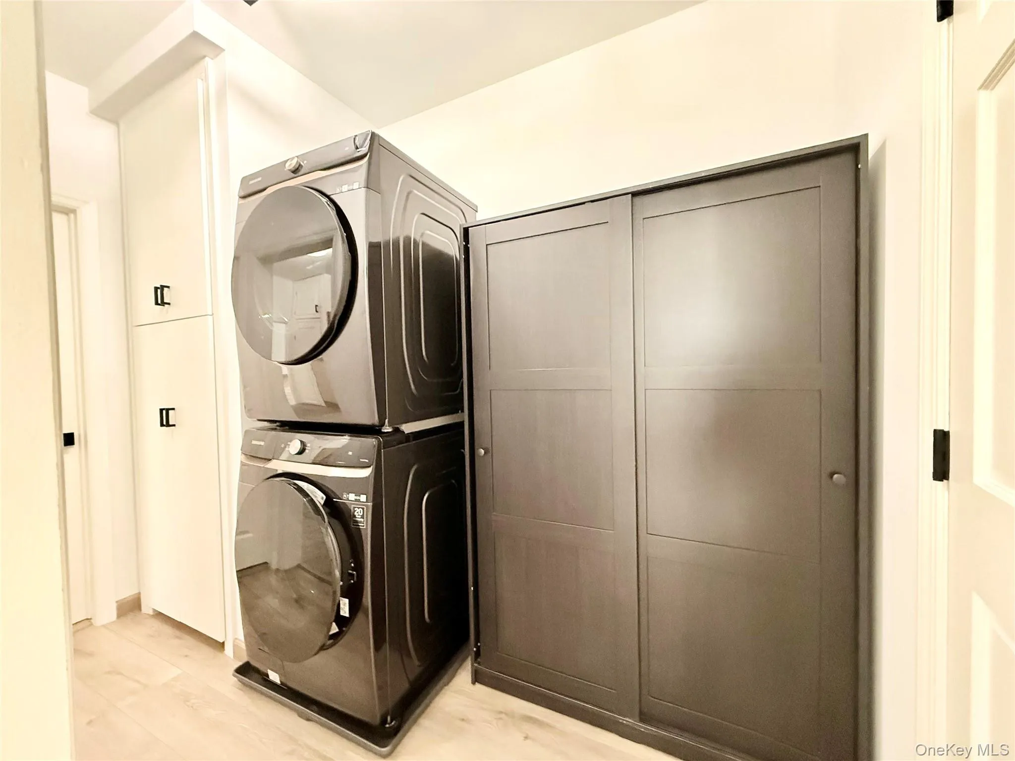 Laundry room featuring light wood-style floors and stacked washing machine and dryer Laundry room featuring light wood-style floors and stacked washing machine and dryer