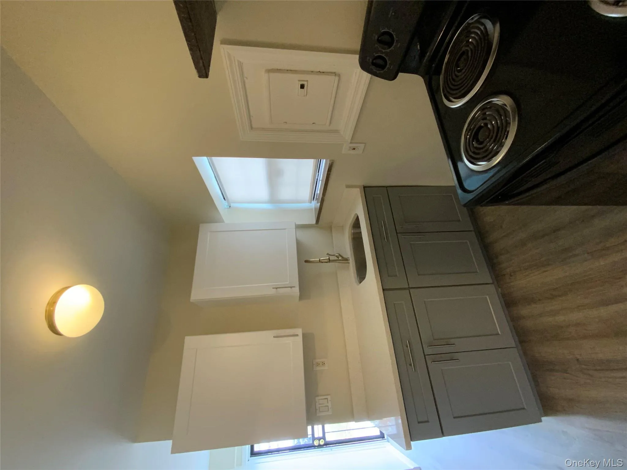 Kitchen with gray cabinetry, range, white cabinets, dark wood-style flooring, and light stone counters Kitchen with gray cabinetry, range, white cabinets, dark wood-style flooring, and light stone counters