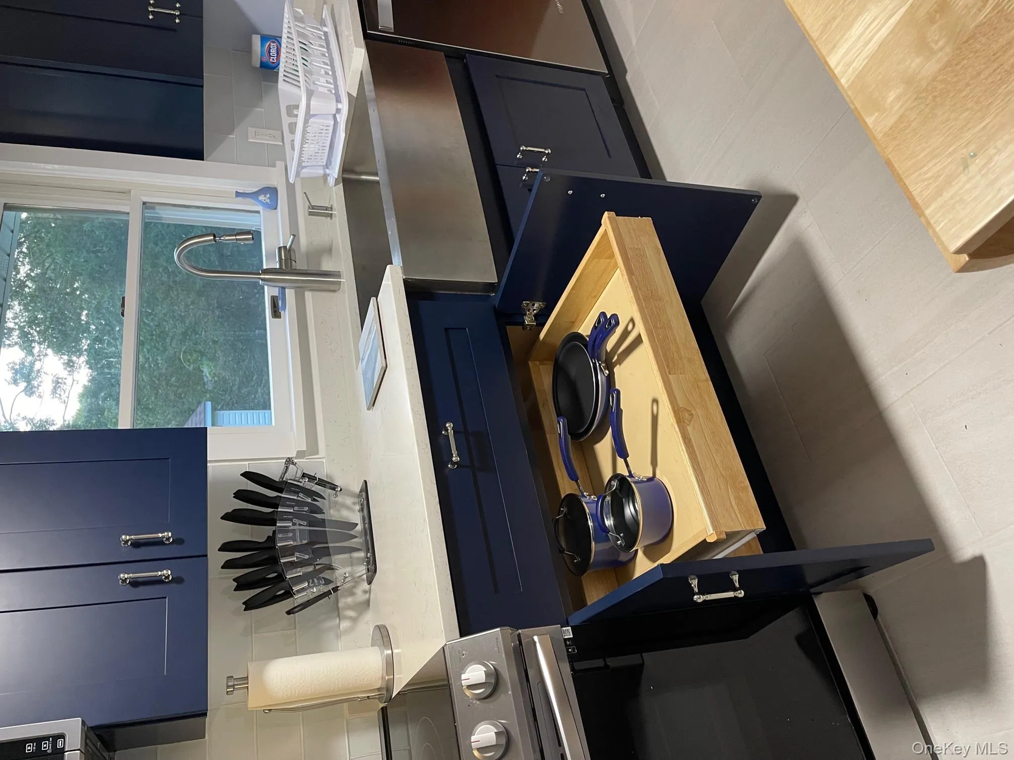 Kitchen with blue cabinetry, decorative backsplash, range, light stone countertops, and dishwasher Kitchen with blue cabinetry, decorative backsplash, range, light stone countertops, and dishwasher