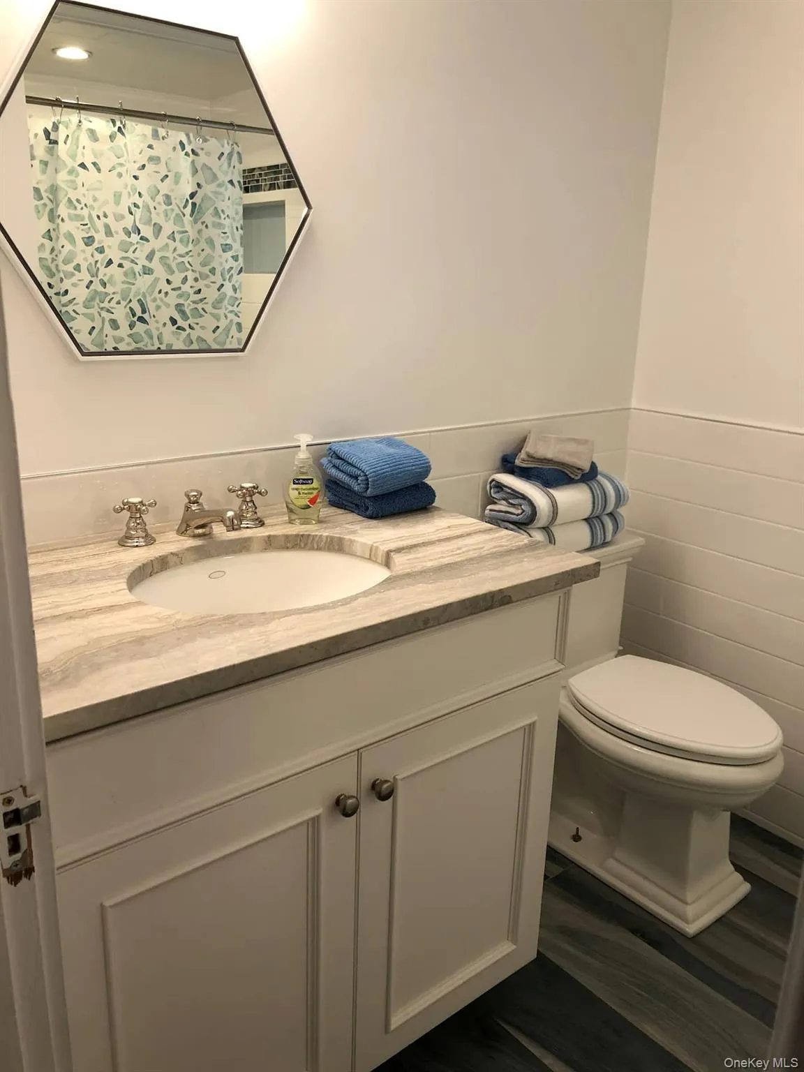 Full bath with vanity, tile walls, a shower with curtain, and a wainscoted wall Full bath with vanity, tile walls, a shower with curtain, and a wainscoted wall