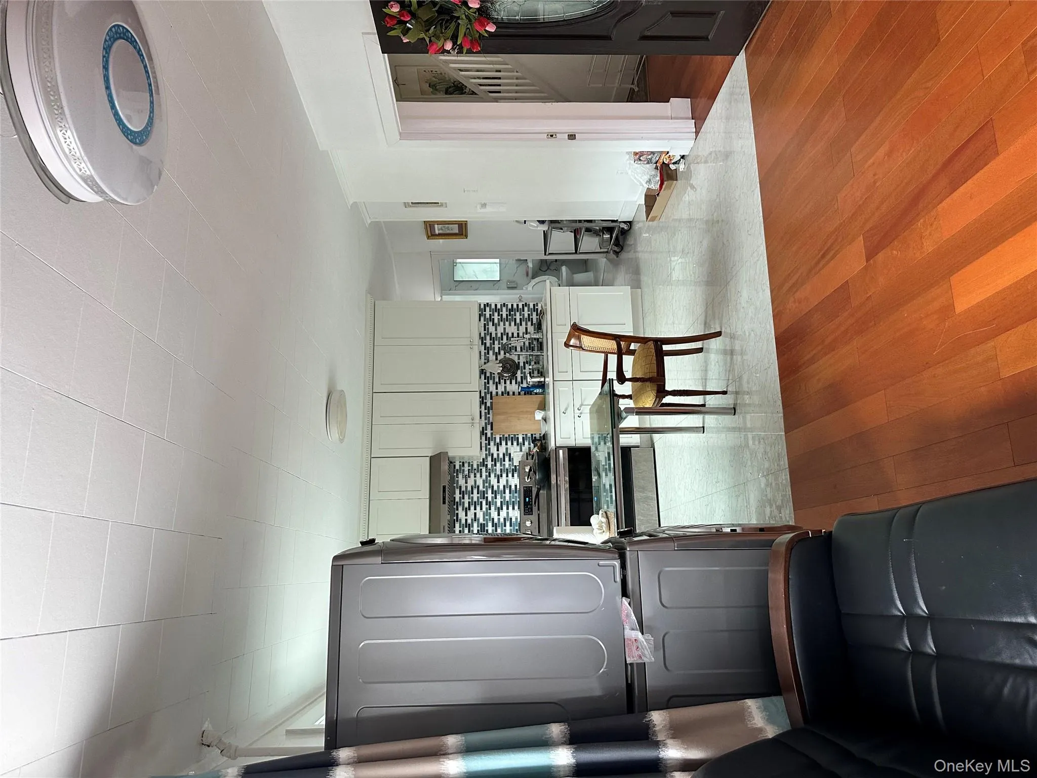Kitchen featuring decorative backsplash, light wood-type flooring, range, and stacked washer / dryer Kitchen featuring decorative backsplash, light wood-type flooring, range, and stacked washer / dryer