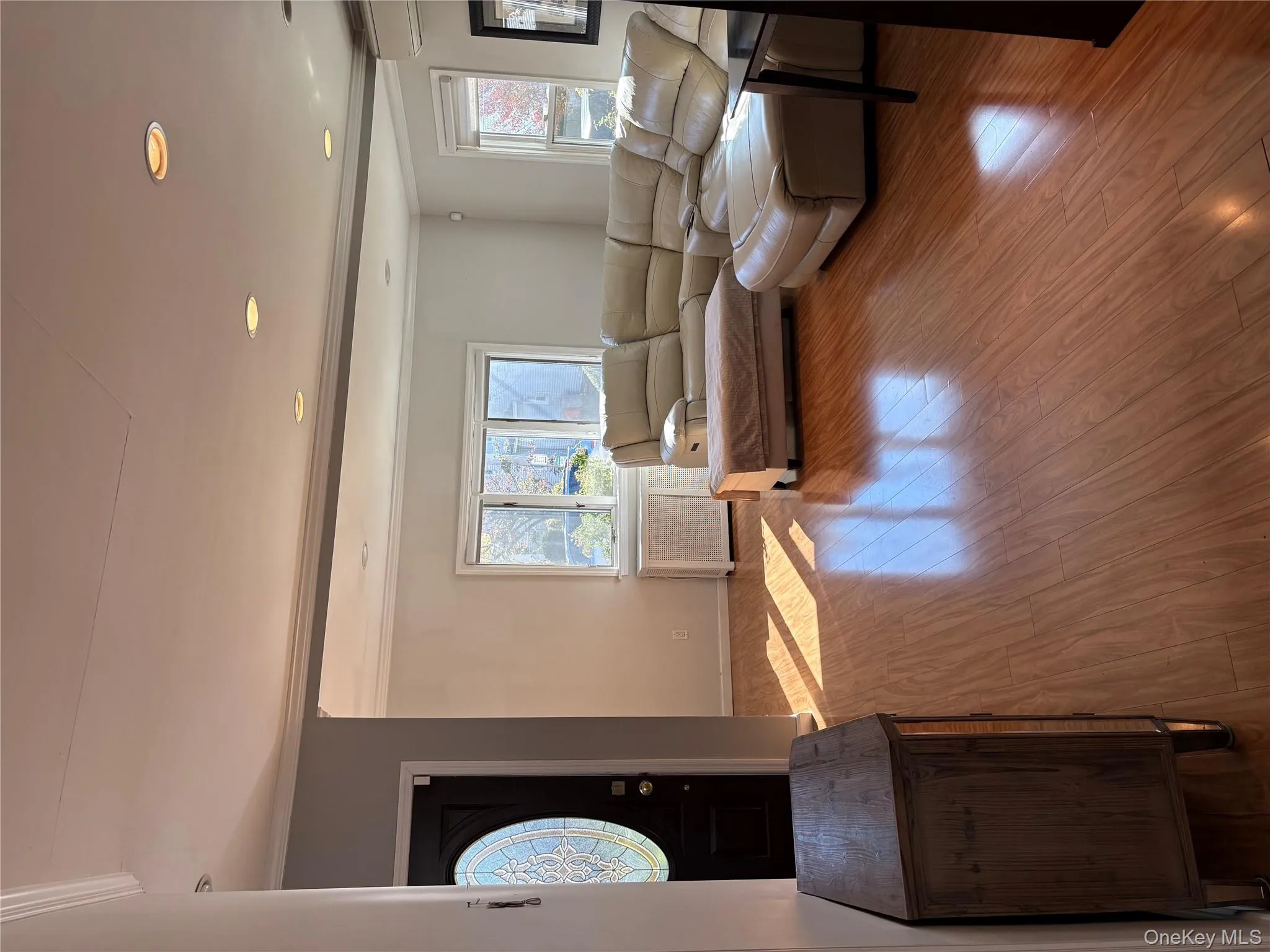 Living room featuring wood finished floors, healthy amount of natural light, crown molding, radiator heating unit, and a wall unit AC Living room featuring wood finished floors, healthy amount of natural light, crown molding, radiator heating unit, and a wall unit AC