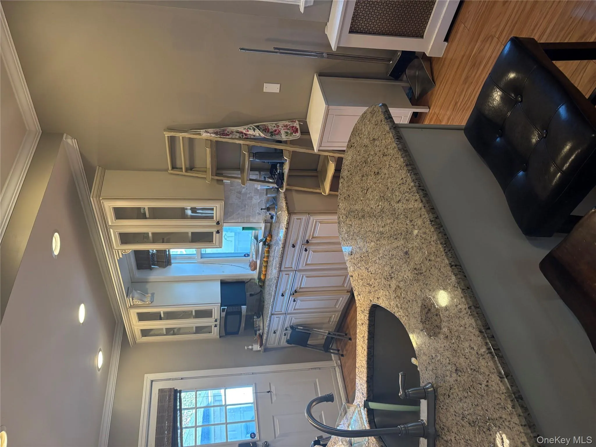 Kitchen featuring ornamental molding, dark wood-type flooring, glass insert cabinets, light stone countertops, and plenty of natural light Kitchen featuring ornamental molding, dark wood-type flooring, glass insert cabinets, light stone countertops, and plenty of natural light