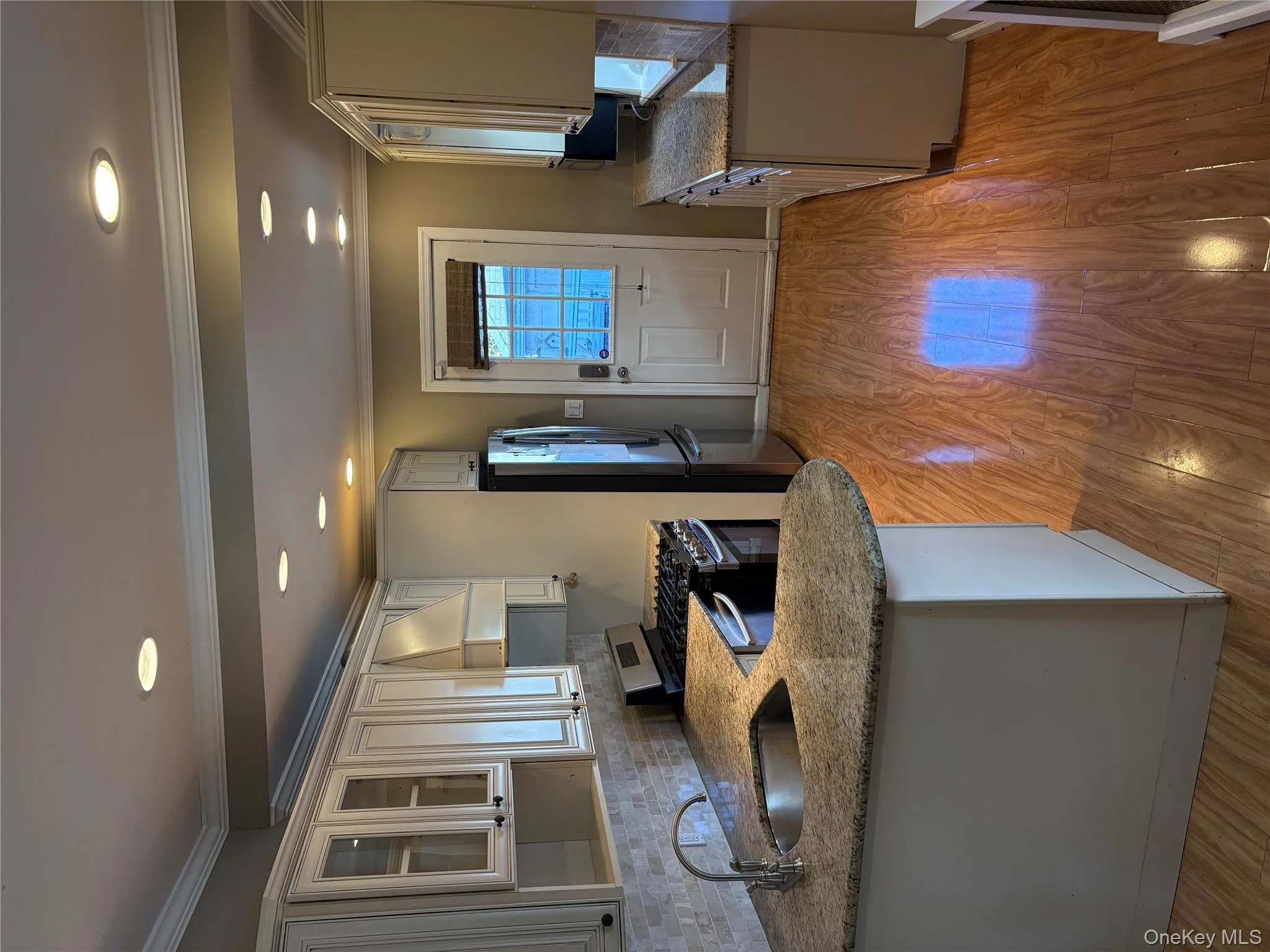 Kitchen with backsplash, ornamental molding, stainless steel appliances, glass insert cabinets, and light wood finished floors Kitchen with backsplash, ornamental molding, stainless steel appliances, glass insert cabinets, and light wood finished floors