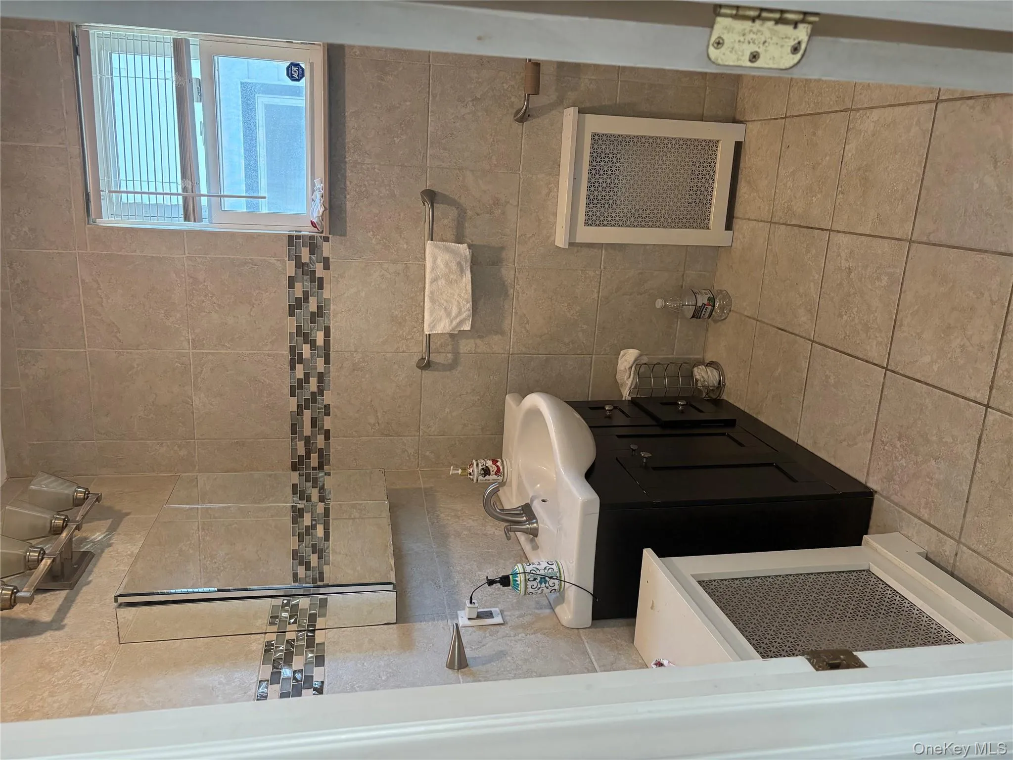 Bathroom featuring tile walls, vanity, radiator heating unit, and light tile patterned floors Bathroom featuring tile walls, vanity, radiator heating unit, and light tile patterned floors