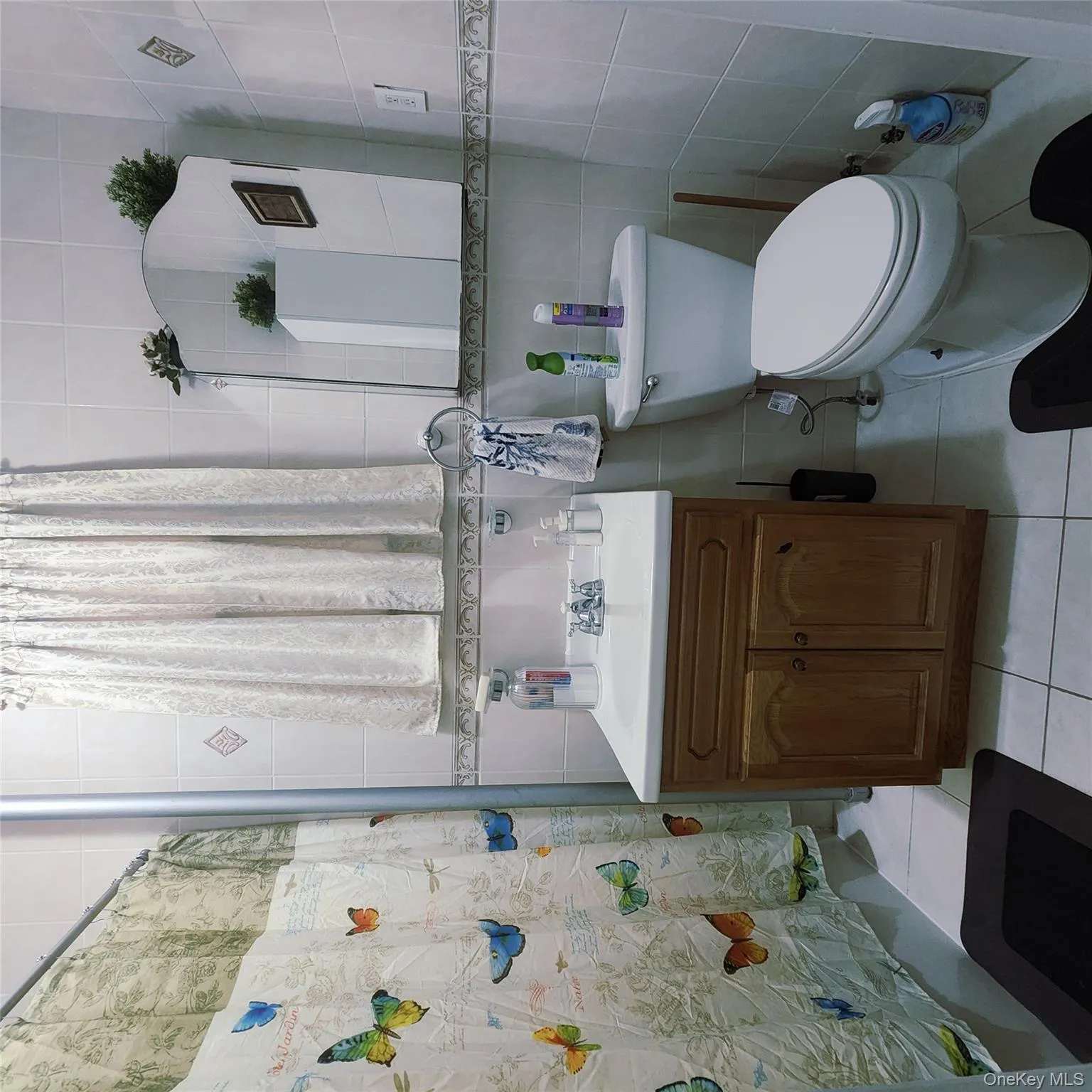 Bathroom featuring tile walls, vanity, curtained shower, and light tile patterned floors Bathroom featuring tile walls, vanity, curtained shower, and light tile patterned floors