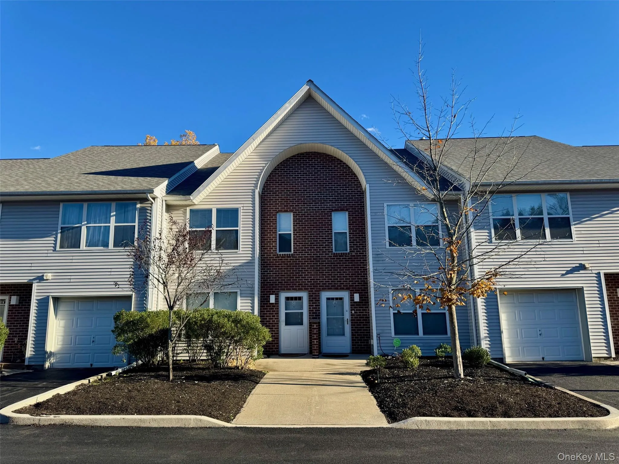 Traditional home featuring driveway, brick siding, a garage, and roof with shingles Traditional home featuring driveway, brick siding, a garage, and roof with shingles